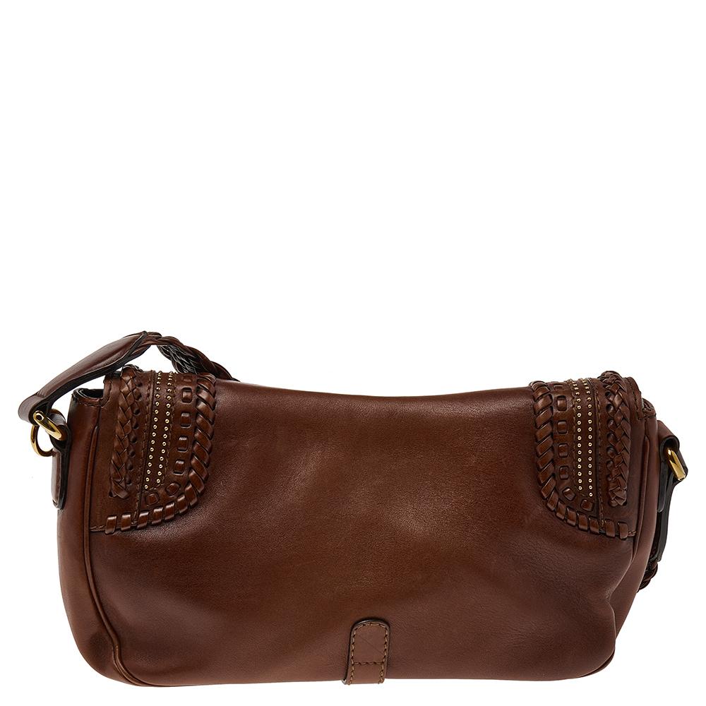 Organize your things in this Gucci Marrakech bag. It is crafted from classic brown leather and features a shoulder strap, gold-tone hardware, and a stitch-detailed front flaunting a gold-tone clasp. It has a suede interior and enough space for your