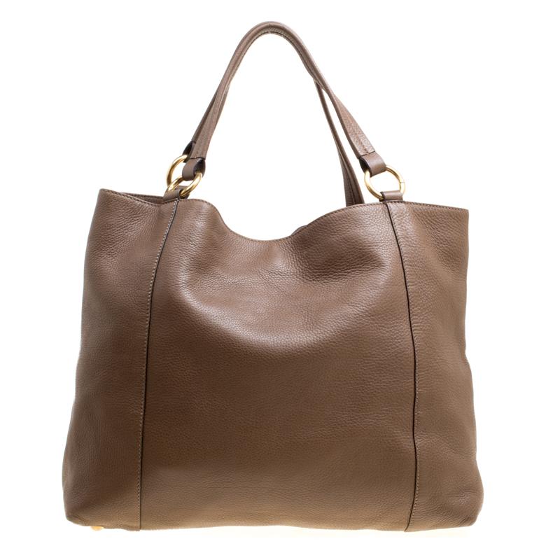 Twill tote from the house of Gucci, one of the most coveted luxury brands, is a pleasant choice for any fashion lover. Designed in smooth, brown leather, this tote comes with two top handles held by ring links. The exterior of the bag features an