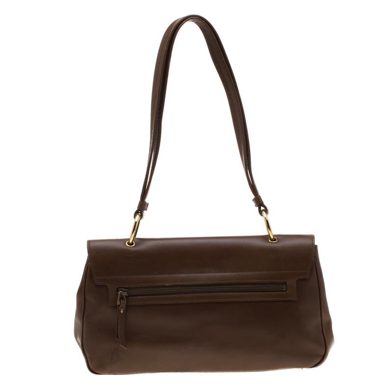 This simple yet elegant Gucci bag is made in Italy and has fine tonal stitching. The shoulder bag is crafted with leather and looks classic in brown. The gold-tone lock closure on the front flap entices the bag's charm. It is complete with a small