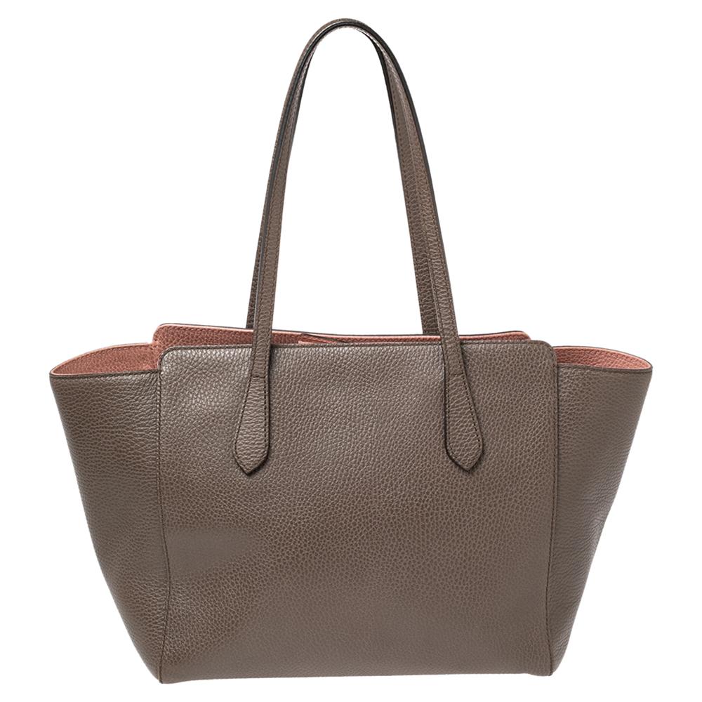 High on appeal and style, this Swing tote is a Gucci creation. It has been crafted into a smart silhouette from leather in Italy and shaped to exude class and luxury. The bag comes with two handles, a spacious interior, and a brand label on the