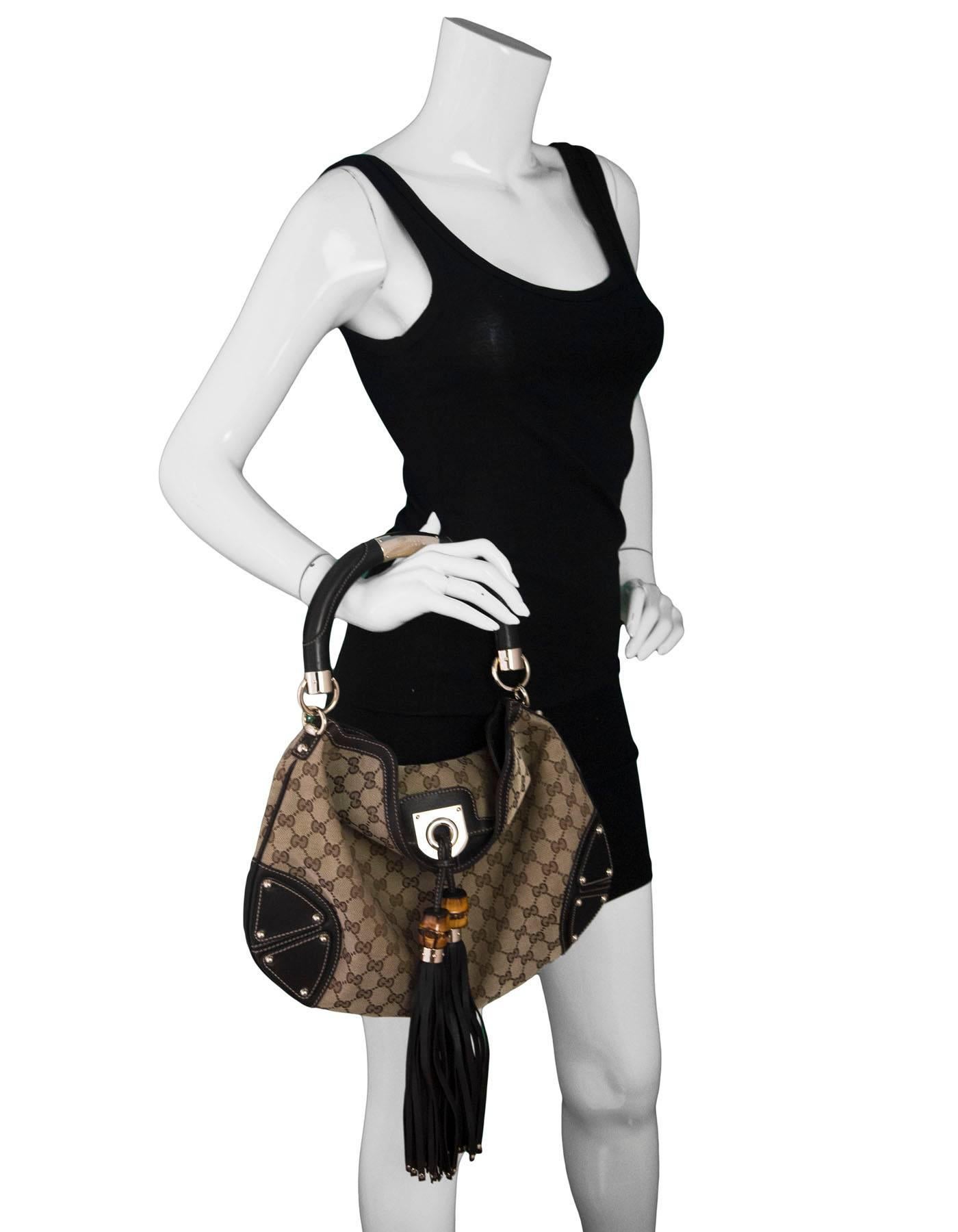 Gucci Brown Monogram Medium Indy Bag
Features tassel ornament

Made In: Italy
Color: Beige, brown
Hardware: goldtone
Materials: Canvas, leather, metal
Lining: Brown textile
Closure/Opening: Open top fold over flap and tassel
Exterior Pockets: