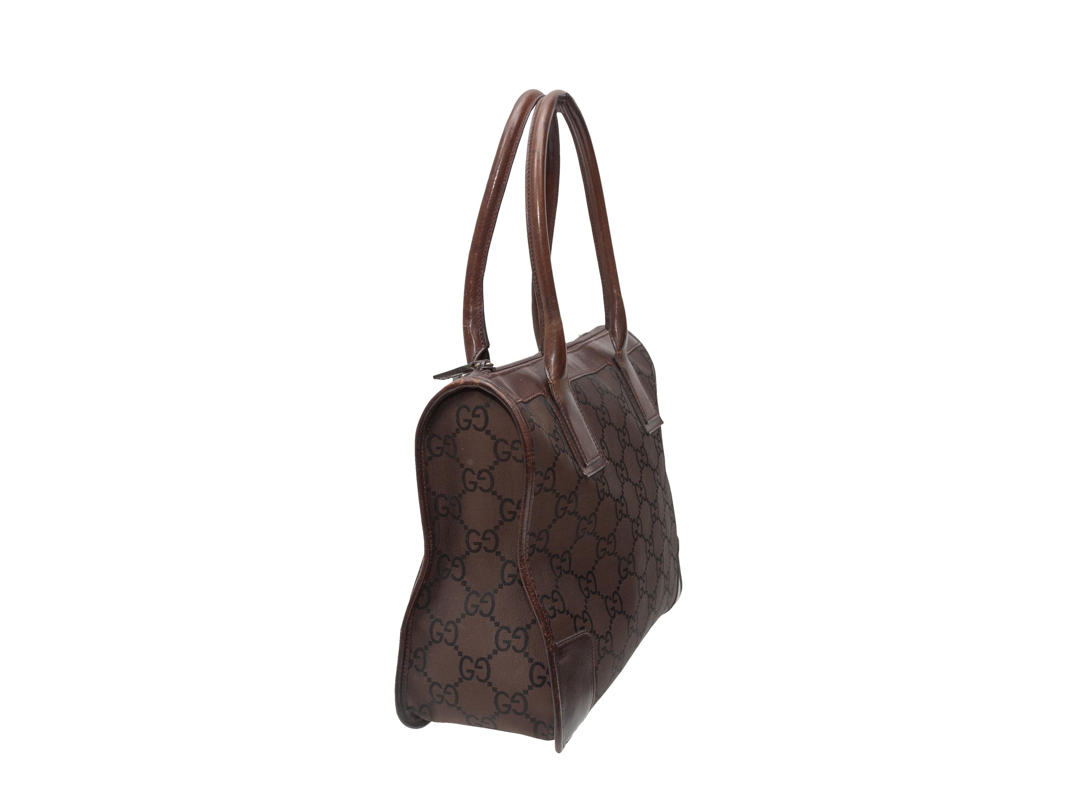 Product details: Vintage brown nylon monogram tote bag by Gucci. Leather trim throughout. Dual top handles. Zip closure at top. 11.75