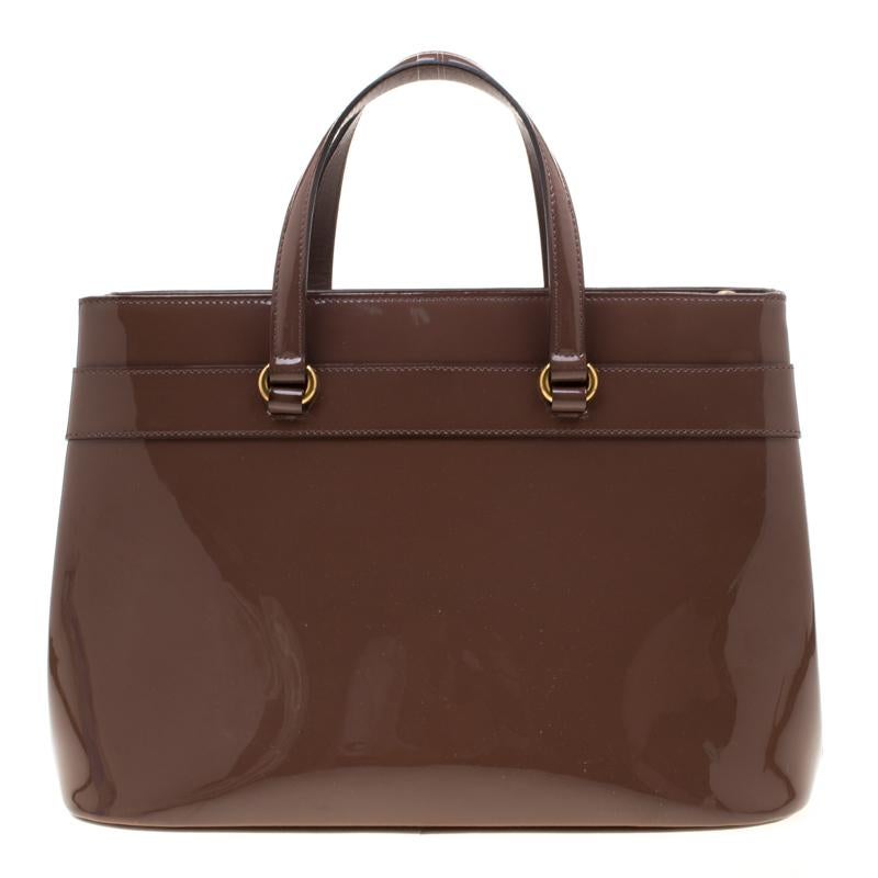 This Bright Bit bag from Gucci proves that style can come in simple things too. Crafted from patent leather, this lovely brown bag features a fabric-lined interior, two top handles, and a long detachable shoulder strap. It is equipped with gold-tone