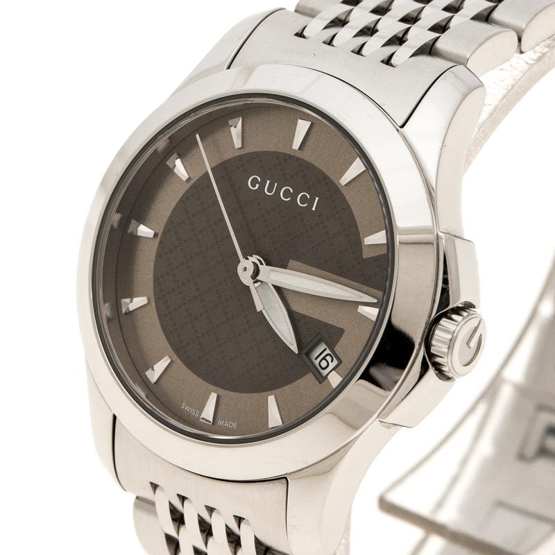 A classic watch in a stainless steel case with a stainless steel link bracelet and a fixed stainless steel bezel. The brown dial with Gucci name embellished on it features luminous silver-tone hands and index hour markers. The analog watch also
