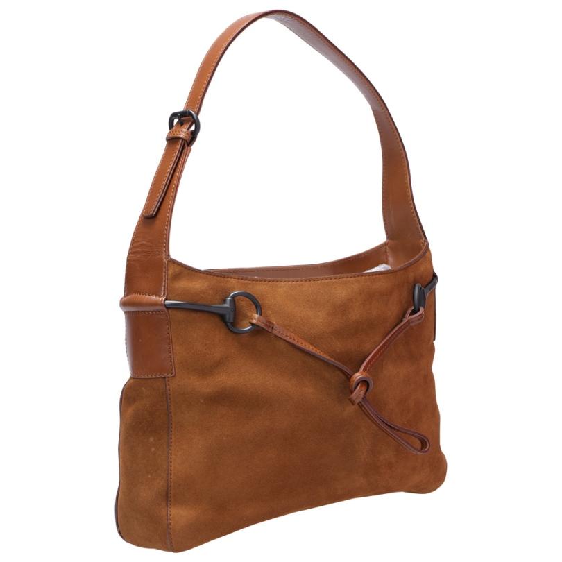 This Horsebit shoulder bag by Gucci is crafted from brown suede and leather. Fine fabric interior ensures to house your essentials safely. Equipped with an adjustable top handle, it has a brilliant finishing and design. Simple and chic is what this
