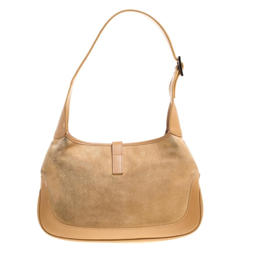 Well-structured and lovely to look at, this Jackie shoulder bag will perfectly complement your feminine attires. The bag is crafted with brown suede and detailed with leather trims. It features a black-tone lock that unfastens to a fabric interior