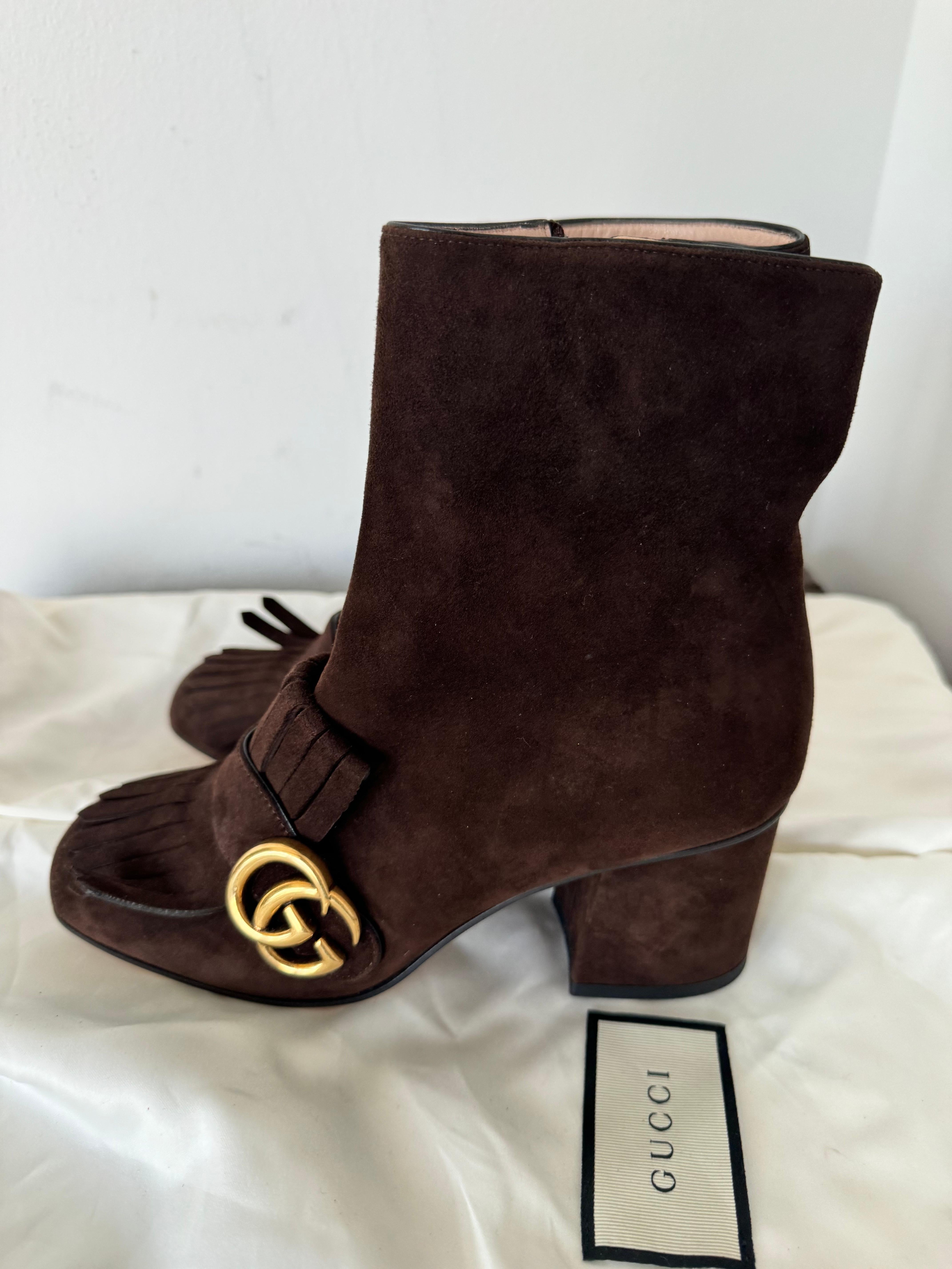 The brand new brown suede Gucci ankle boots you've described are a beautiful blend of sophistication, luxury, and signature Gucci detailing.

Material and Color:
Crafted from rich brown suede, these ankle boots exude elegance and timeless style.