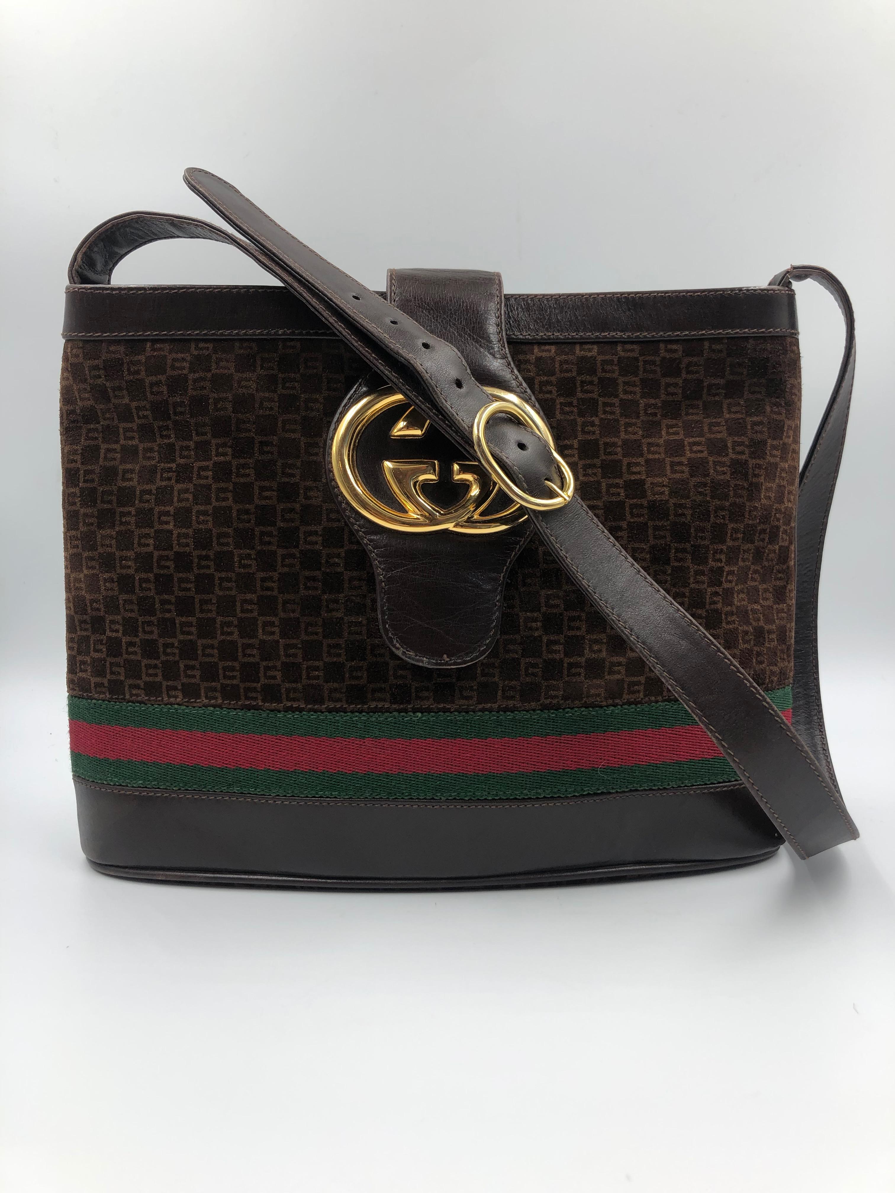 Gucci Brown Suede Bucket Bag with leather Snap Closure. Brown leather and woven Gucci signature red and green fabric stripe around the bottom of the bag. Brown leather adjustable crossbody shoulder strap with belt style closure.

Measurements taken