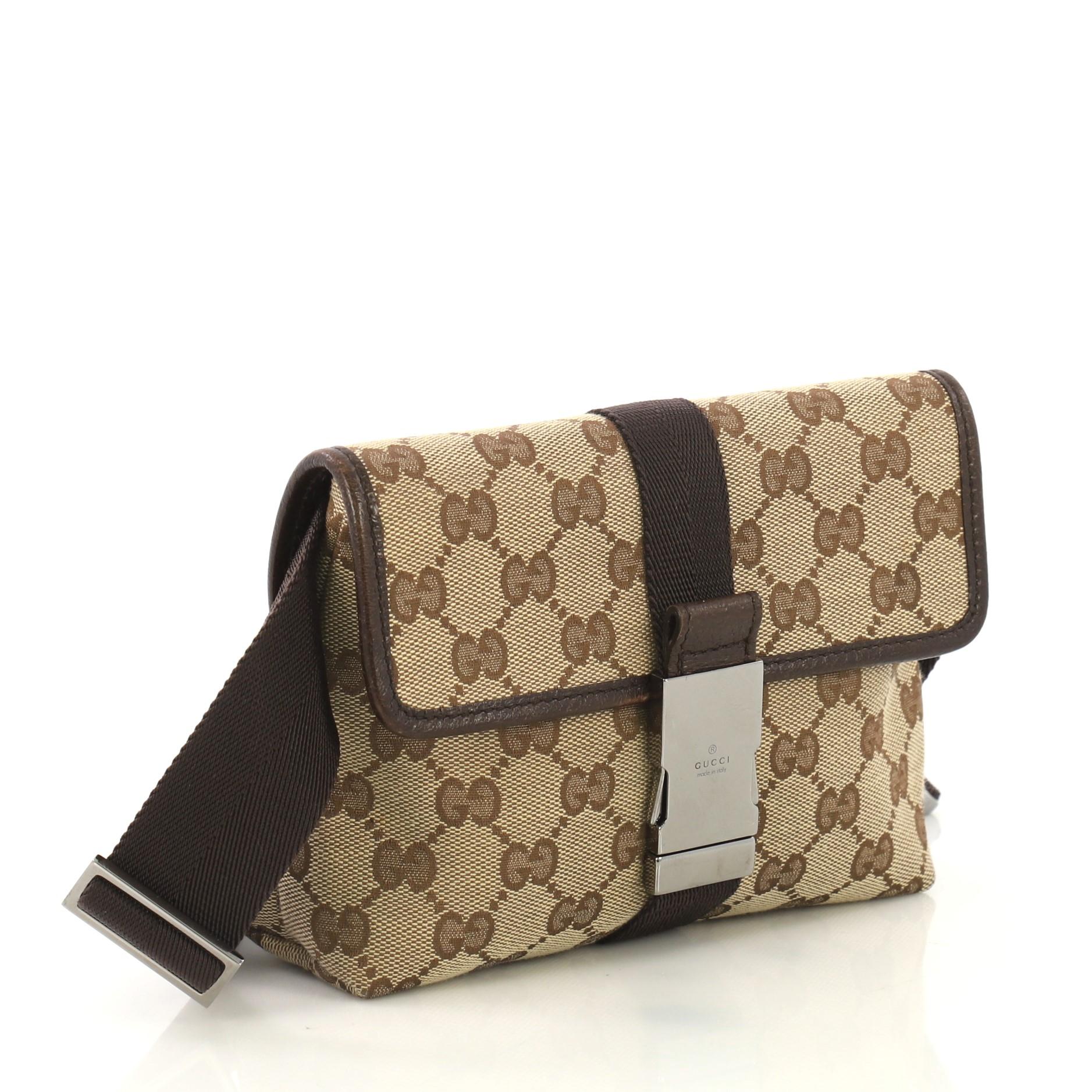 This Gucci Buckle Waist bag GG Canvas Small, crafted in brown GG canvas, features an adjustable waist strap, leather trims and gunmetal-tone hardware. Its buckle closure opens to a brown fabric interior with zip pocket. 

Condition: Very good. Wear