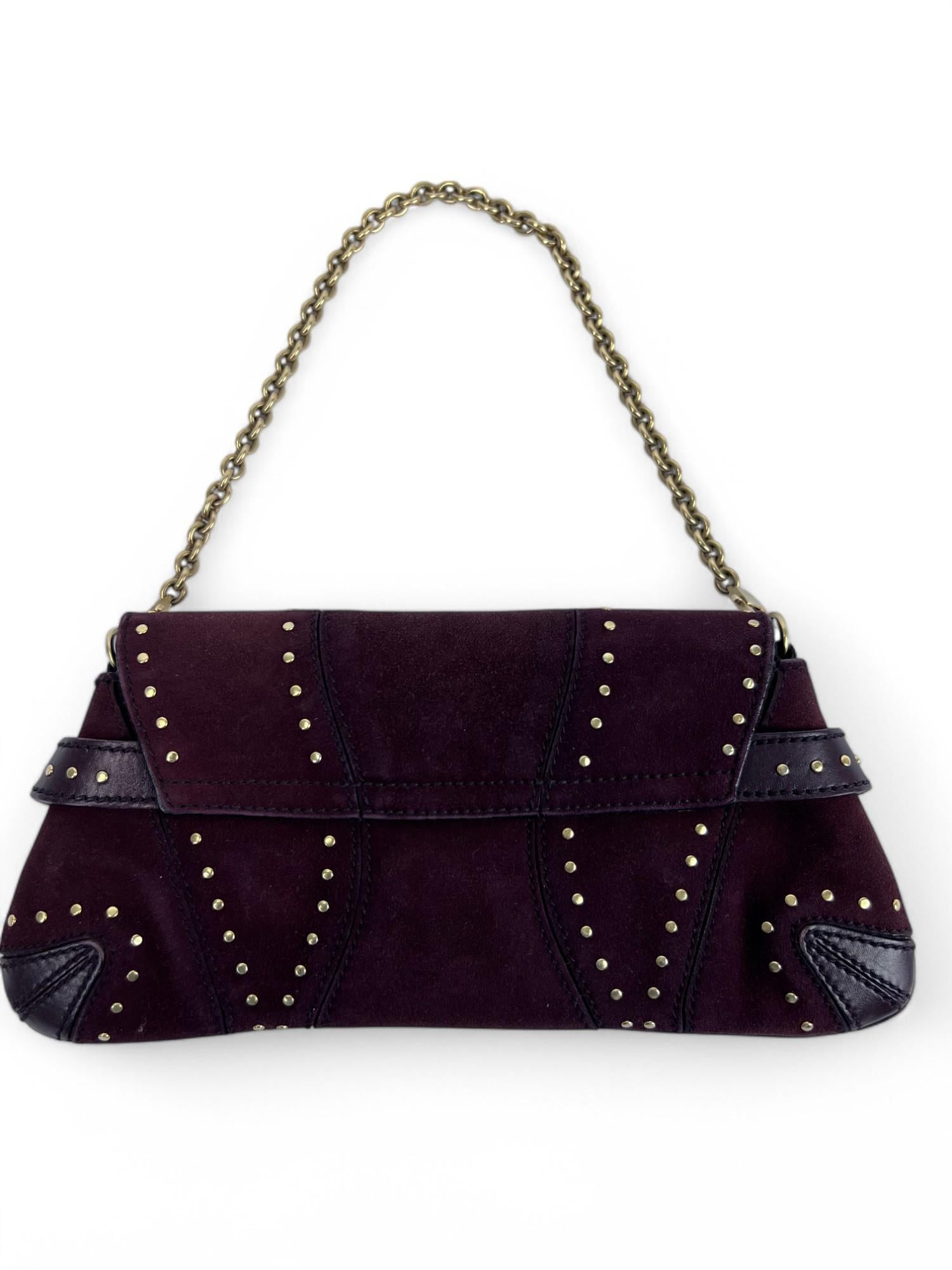 A striking fusion of rich textures and bold detailing, this Gucci Horsebit Chain Clutch is crafted from supple burgundy leather and soft suede, creating a luxurious contrast. The design is elevated with gleaming gold-tone studs that add a touch of