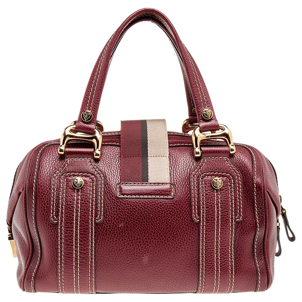 A truly posh and elegant piece to add to your collection. This Aviatrix Boston bag by Gucci is crafted from grained leather and styled with a flap that carries an emblem for a lock. It also has a top zip closure, two handles, protective metal feet,