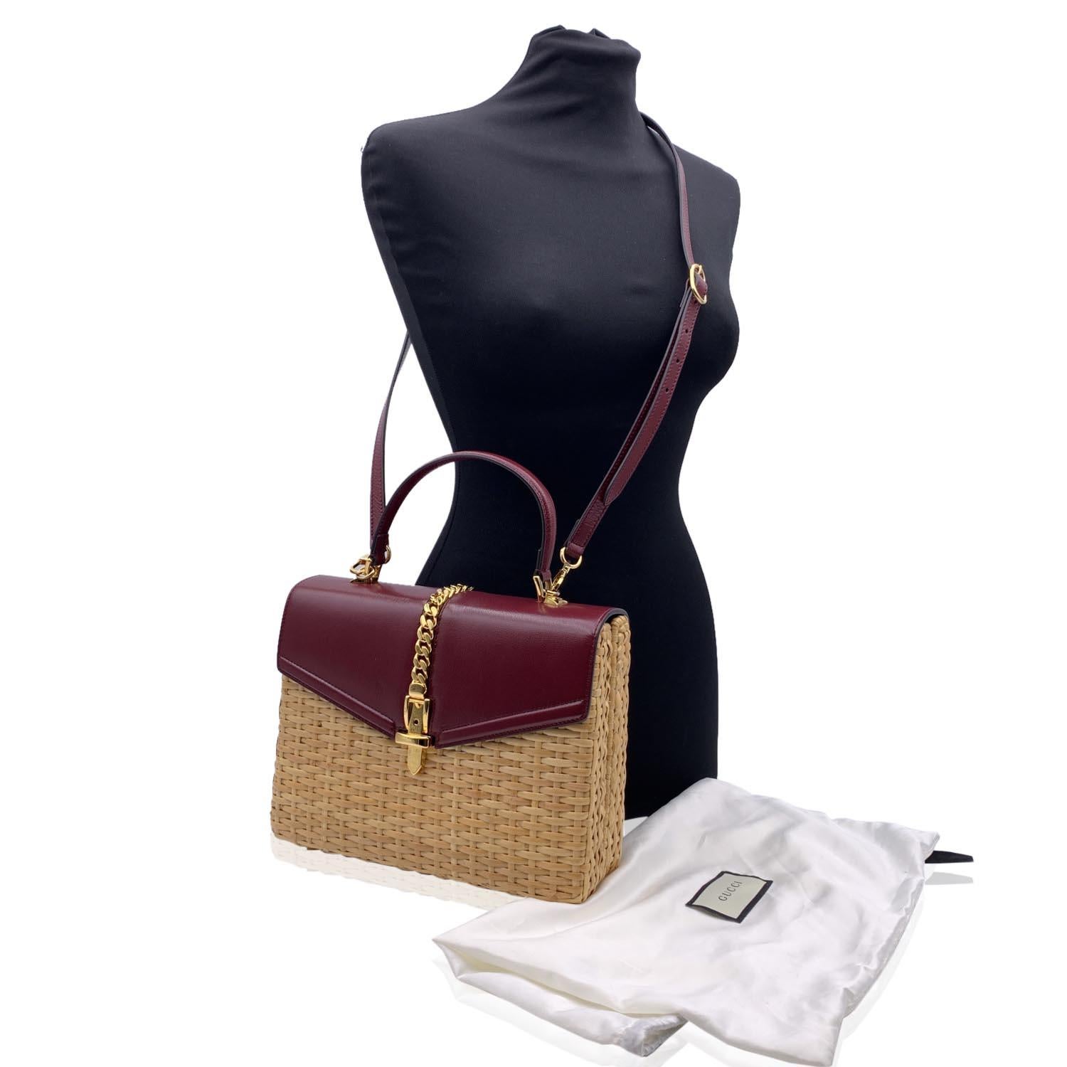 Stunning 'Sylvie' top handle bag by Gucci., from the Pre-Fall 2019 collection. This is the small version of the Sylvie satchel line, now discontinued. It is crafted in beige wicker and smooth burgundy leather with gold metal chuncky chain on top.
