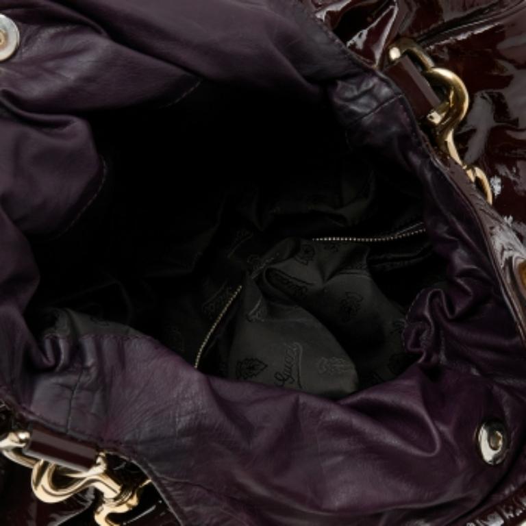 Este bolso tote Gucci Hysteria está pensado para el uso diario. Fabricado en polipiel, tiene un exterior burdeos y dos asas para que puedas pasearlo fácilmente. El interior de nailon está bien dimensionado y el bolso se completa con emblemas dorados