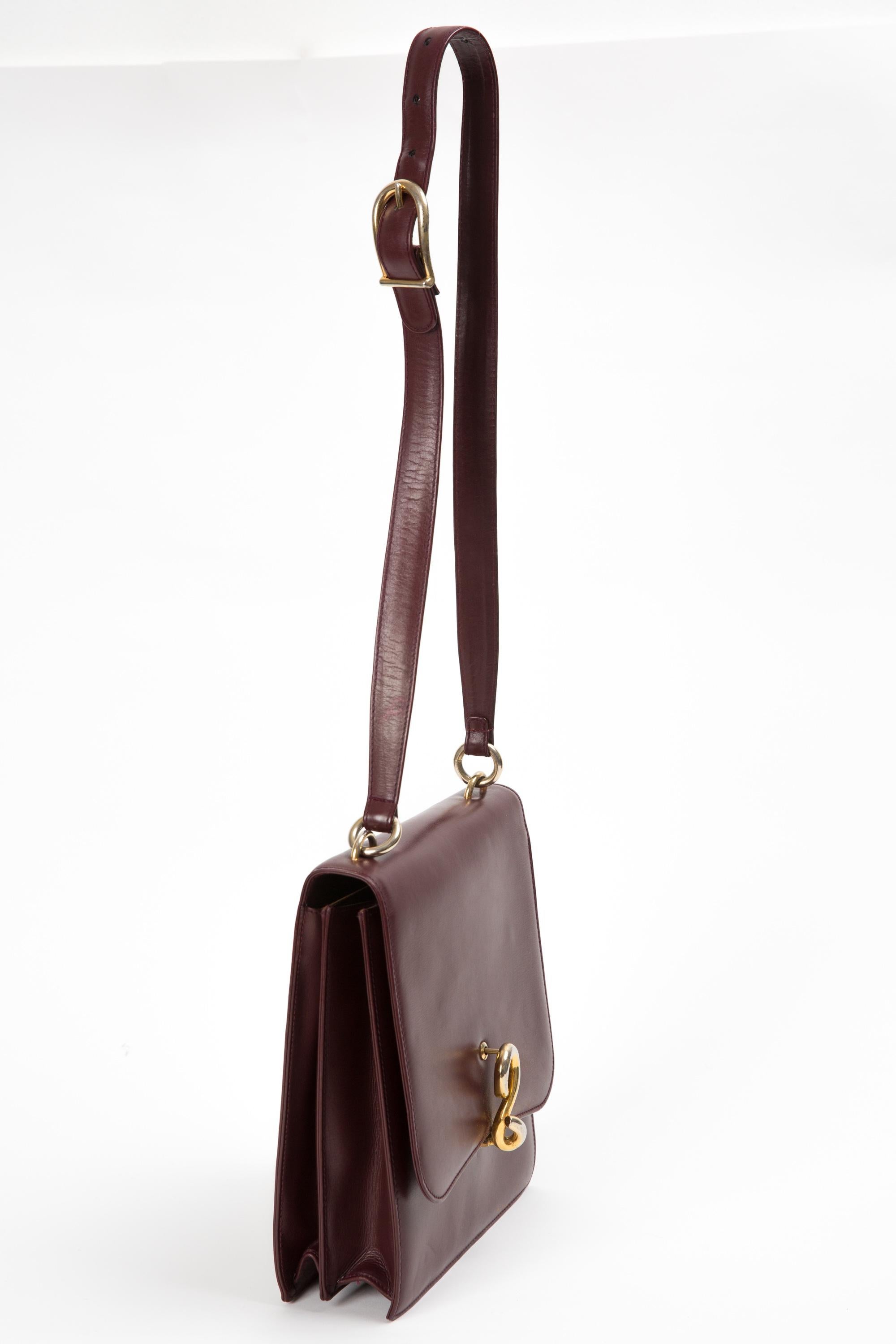 Gucci burgundy calf leather shoulder bag featuring gold tone hardware with front clasp closure, an adjustable shoulder/crossbody strap, beige leather lining with inner slip and zipper pocket and an inside gold tone printed logo.
In good vintage