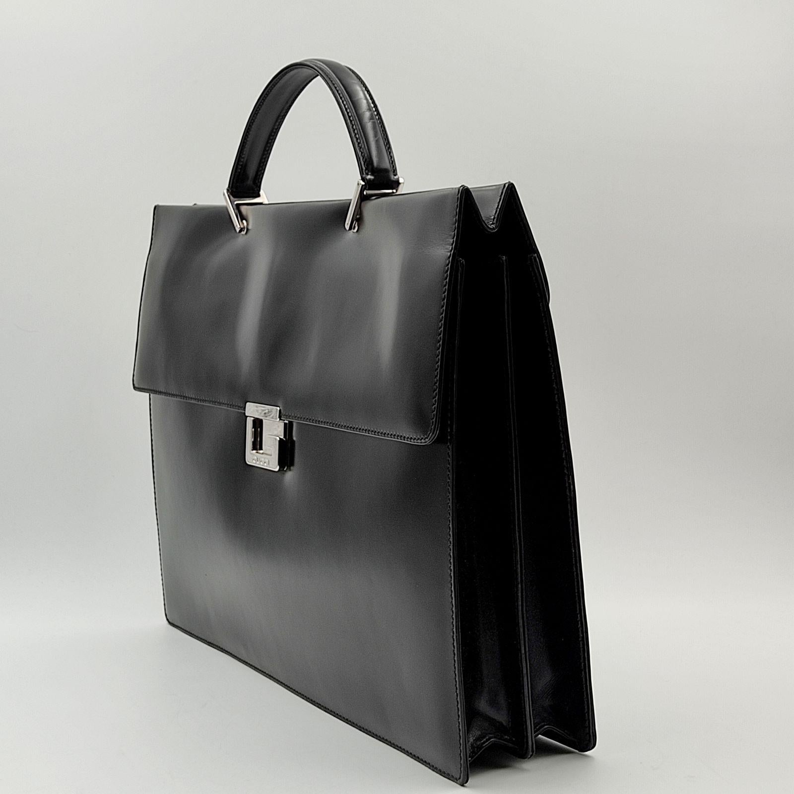 Borsa business Gucci in pelle nera. Finiture in acciaio. Chiusura a scatto, spinta verso il basso. Interno con due scomparti in tessuto scamosciato beige, dotato di tasche organizer.

Note: Non è mai stato usato ma presenta graffi impercettibili