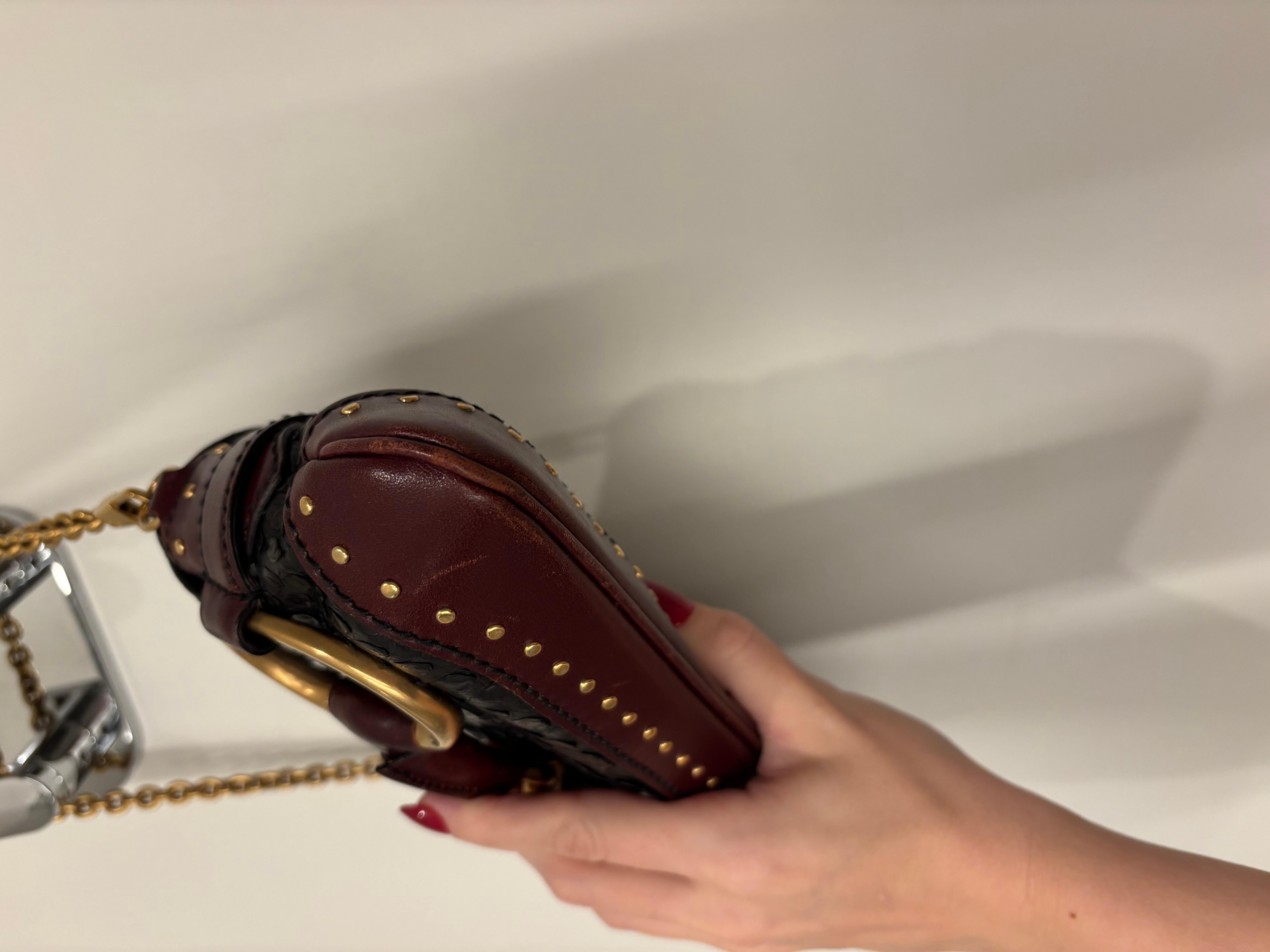 Tom Ford for Gucci
FW03
Vintage
Black Leather made to mimic snakeskin
Yellow Gold hardware and studs
Burgundy Leather trim
Vintage condition
Measurements in inches laying flat: length along bottom at longest point 11 at shortest along the top flap