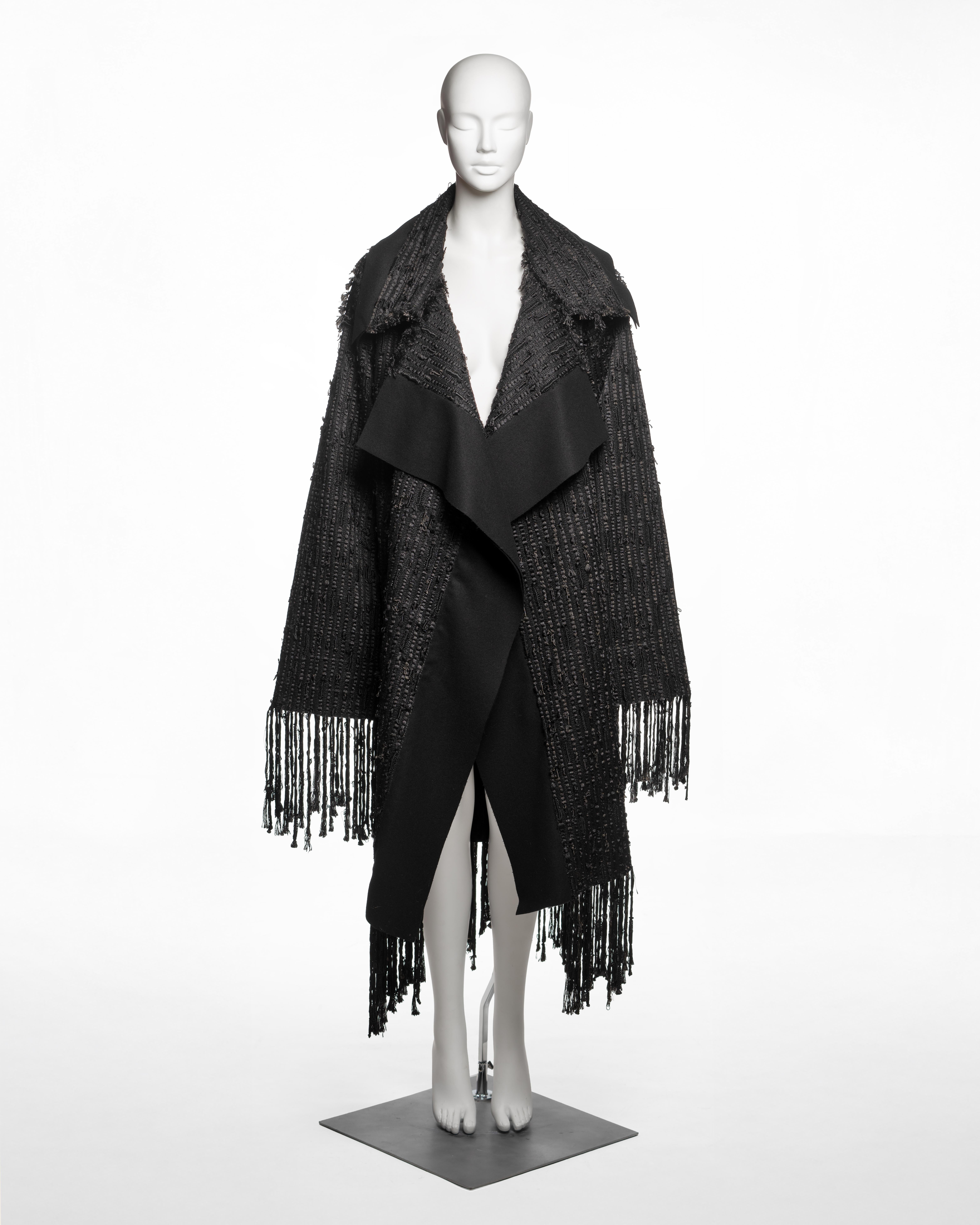 Cappotto oversize aperto di Gucci by Tom Ford, Autunno-Inverno 2002, mostrato come Look 2 in passerella e presente nella campagna pubblicitaria ufficiale fotografata da Mario Testino. Il cappotto è realizzato in tessuto bouclé nero a trama fitta,