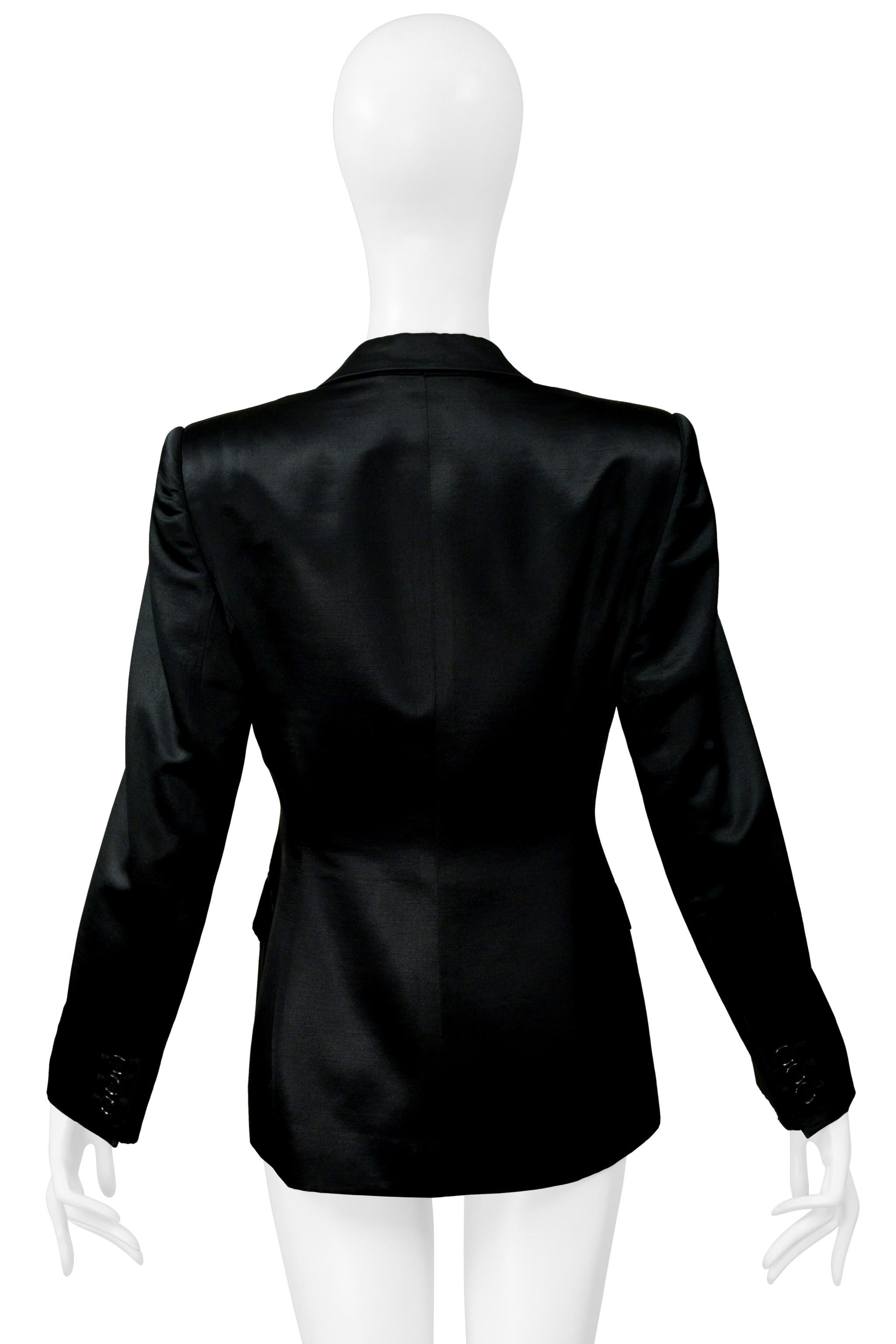 Resurrection Vintage è entusiasta di presentare una giacca da sera vintage in raso nero di Tom Ford for Gucci. Questa giacca è caratterizzata da una chiusura a un bottone, dettagli classici della sartoria, tasche anteriori, polsini con bottoni ed è