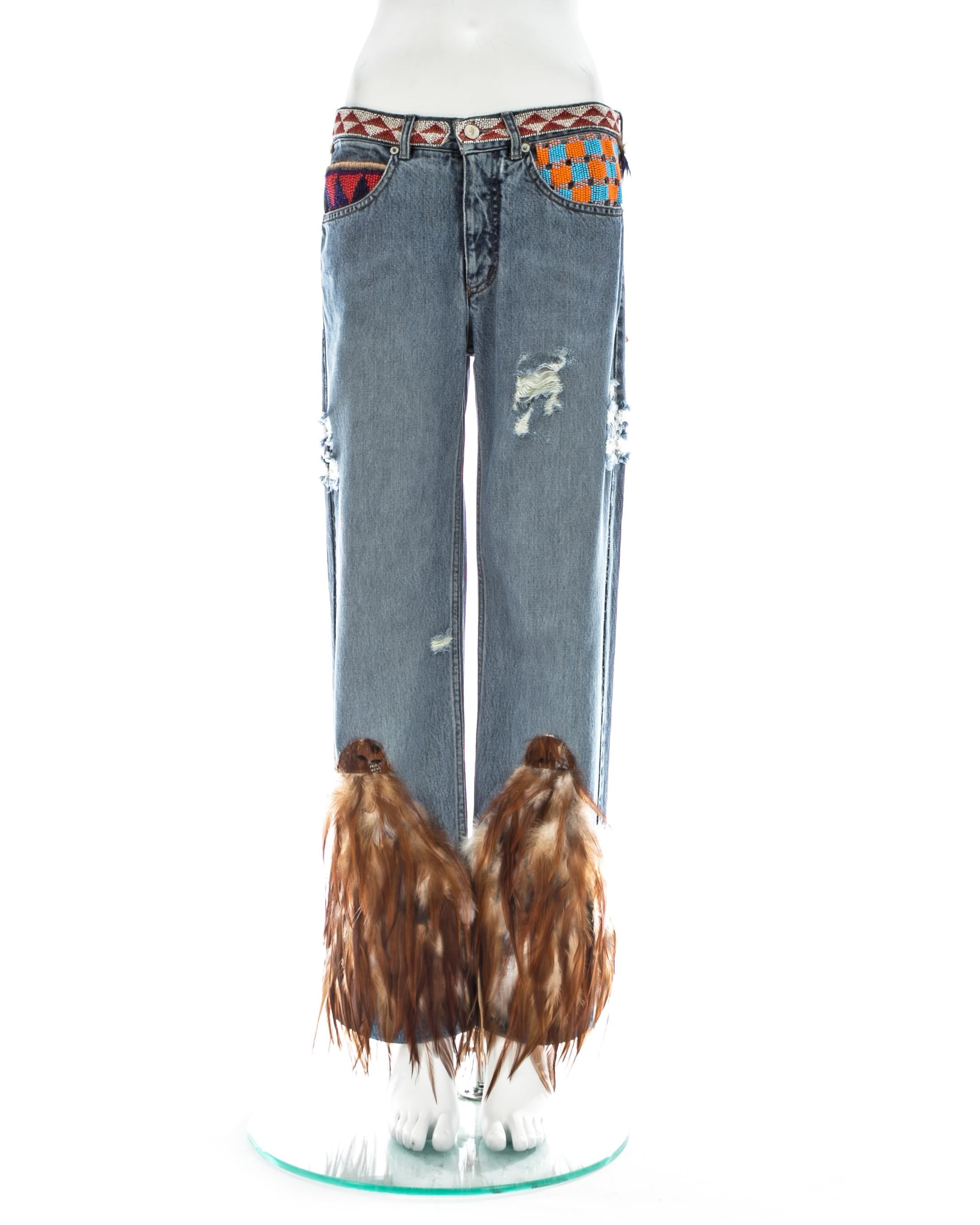 Gucci by Tom Ford; Light blue distressed denim jeans with multicolour beading and feather trim around leg opening.

Spring-Summer 1999