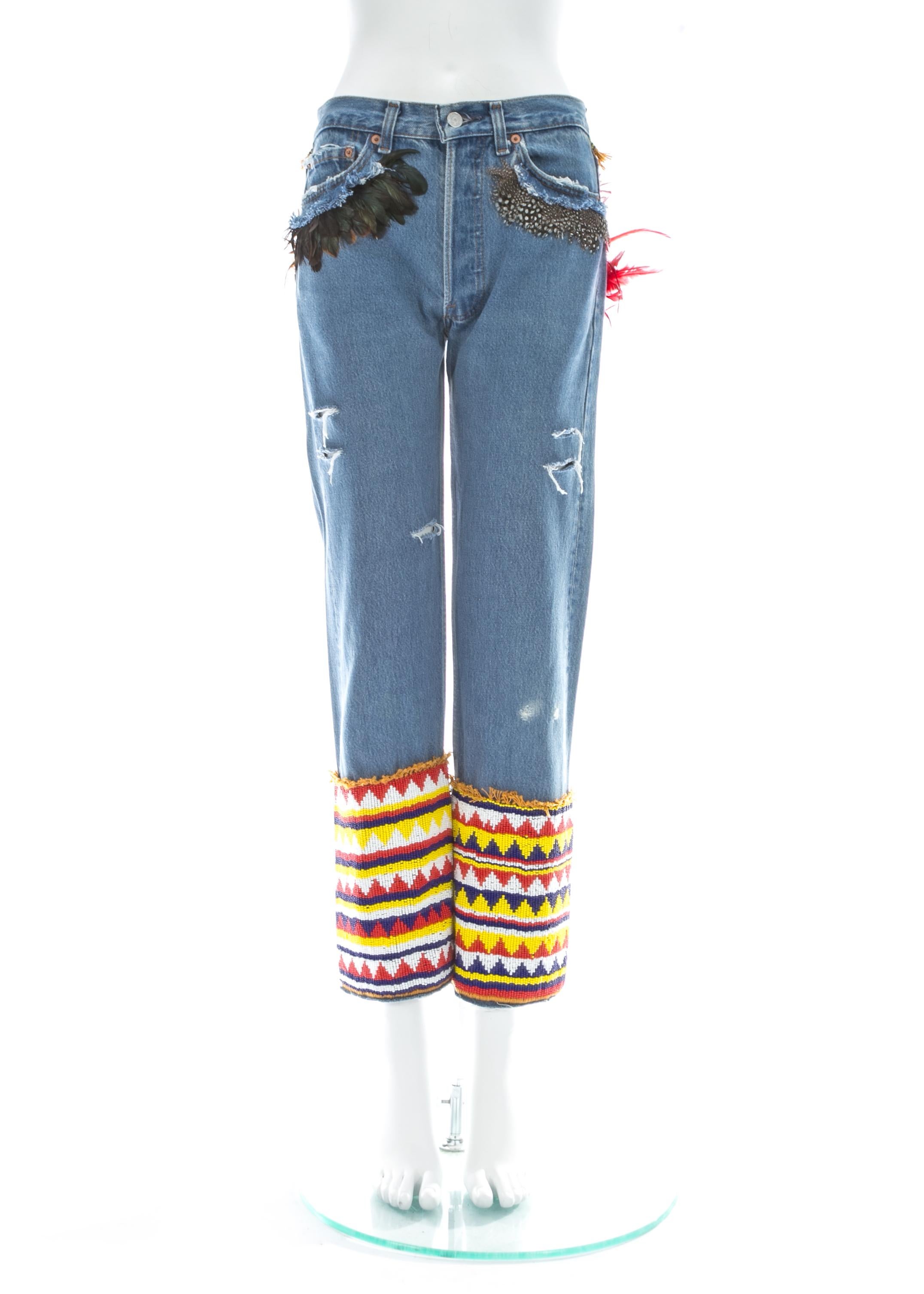 Gucci by Tom Ford; Light blue distressed denim slim-fit Levi jeans with feather trim around pockets and multicolour beading around leg opening.

Spring-Summer 1999

