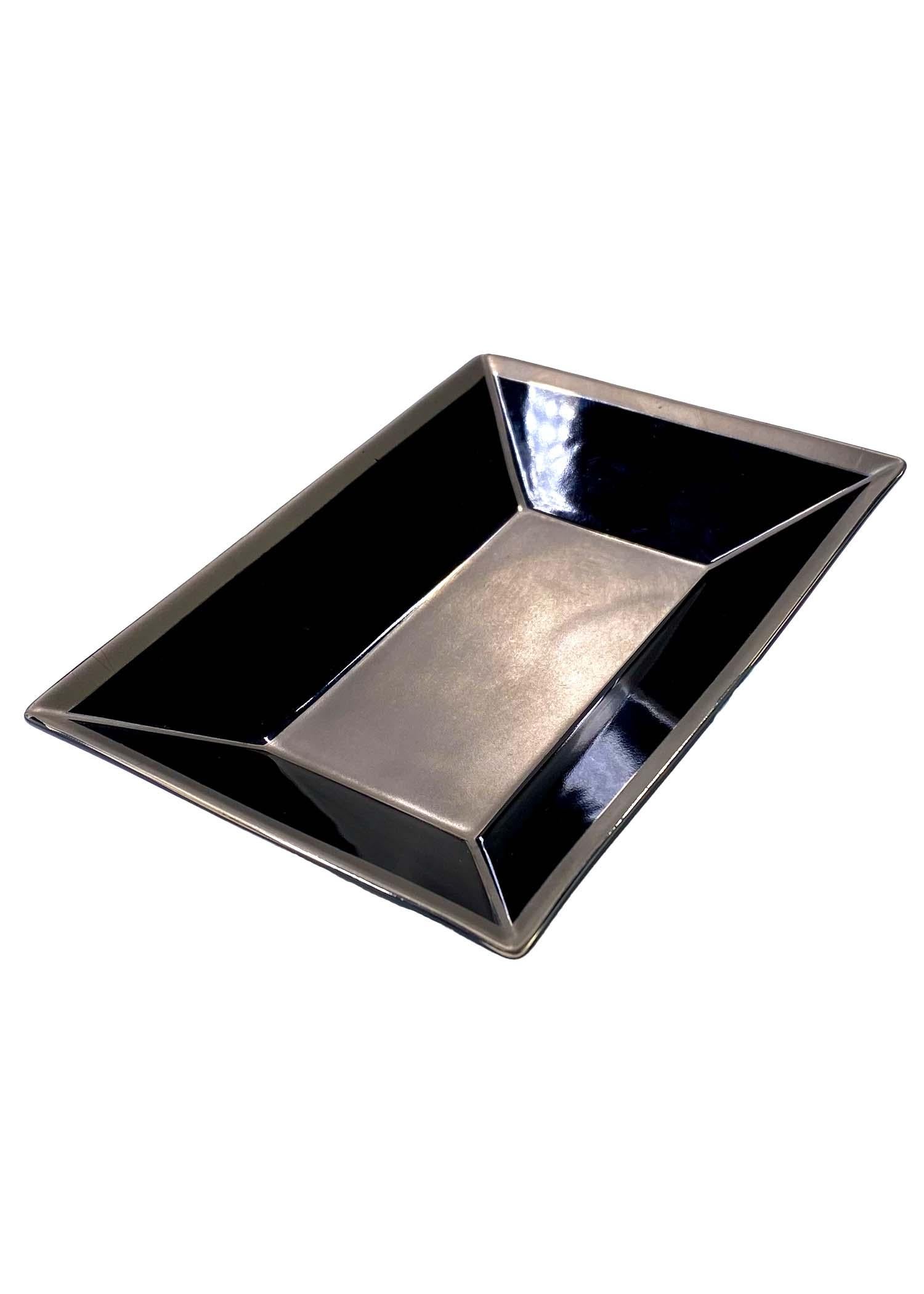 TheRealList presents: a small Gucci change tray, designed by Tom Ford. This black ceramic tray has a platinum finish and speaks to Tom Ford's simple and chic designs. The small tray matches other ceramics from Gucci's home line from the Tom Ford era