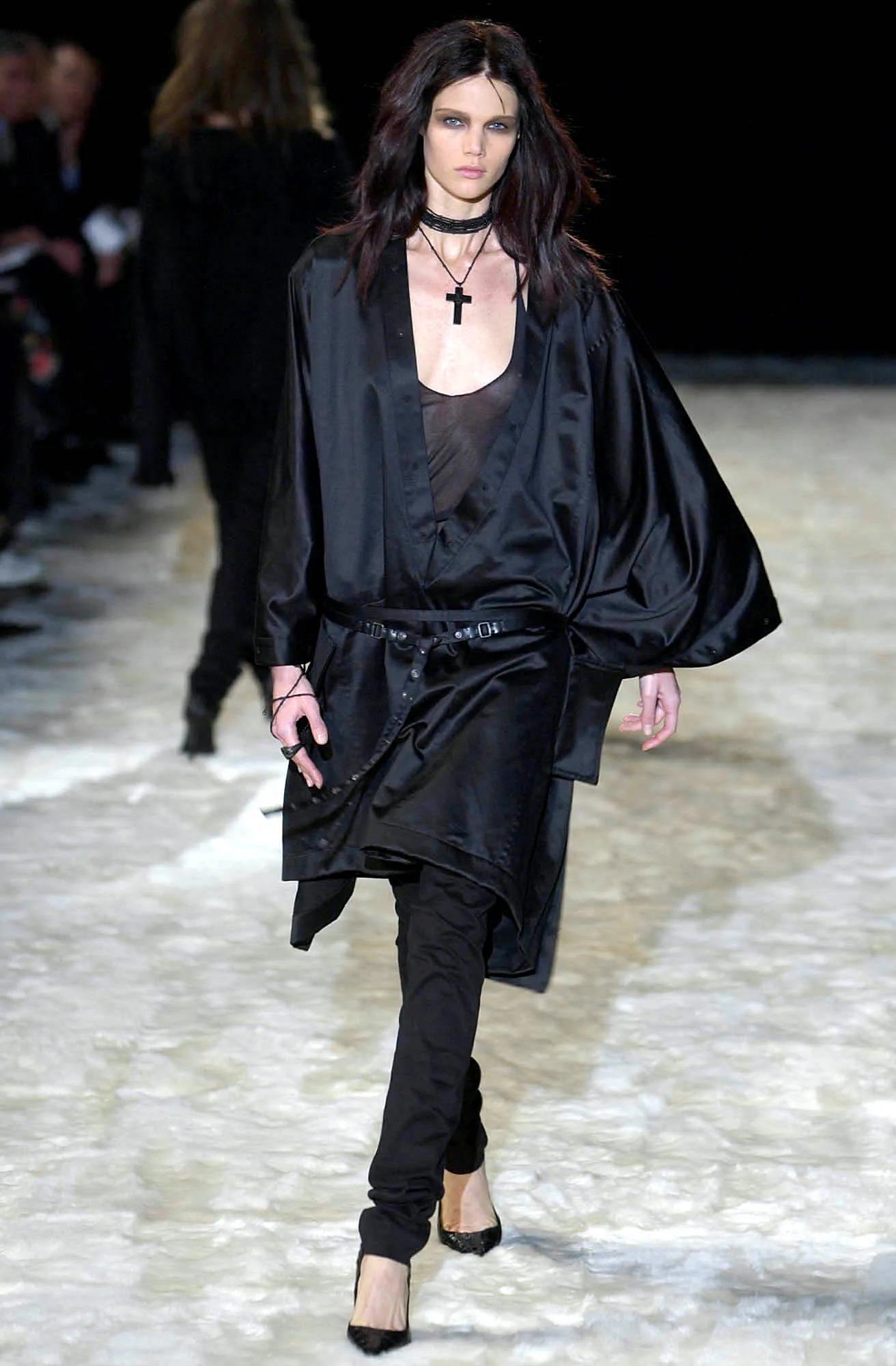 Esta chaqueta de piel de oveja negra, pieza icónica de la colección Gucci Otoño/Invierno 2002 de Tom Ford, ejemplifica la estética sensual y estructurada característica de Ford. Este diseño versátil, fabricado en Italia con piel auténtica flexible y