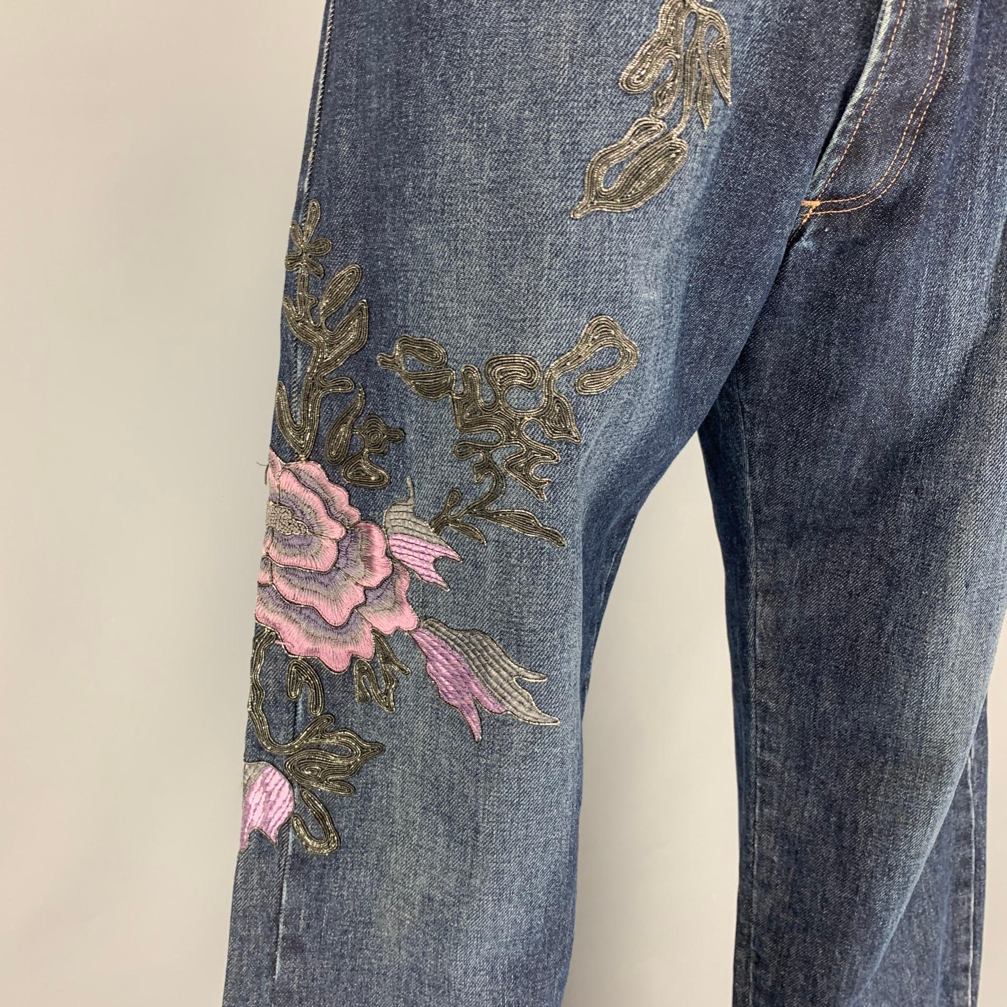GUCCI by Tom Ford Fall 1999 jeans comes in a blue denim cotton featuring a relaxed fit, lavender floral embroidered designs, contrast stitching, and a button fly closure. Made in Italy. 

Very Good Pre-Owned Condition.
Marked: