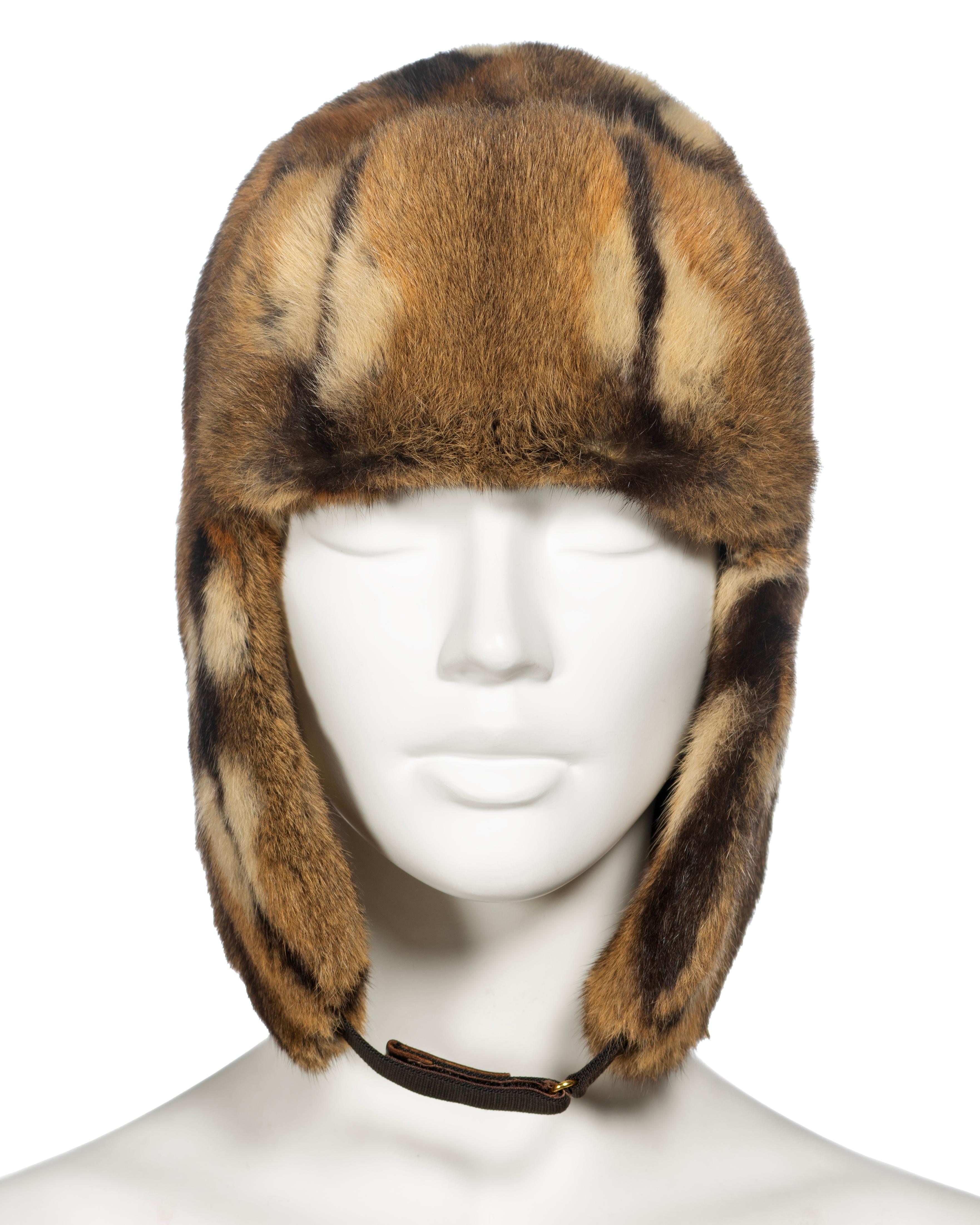 ▪ Gucci Fur Trapper Hat
▪ Creative Director: Tom Ford
▪ Fall-Winter 2000
▪ Sold by One of a Kind Archive
▪ Brindled multi-tone fur
▪ Brown leather strap with velcro fastening 
▪ Size: Small
▪ Made in Italy   

The photographs presented in this