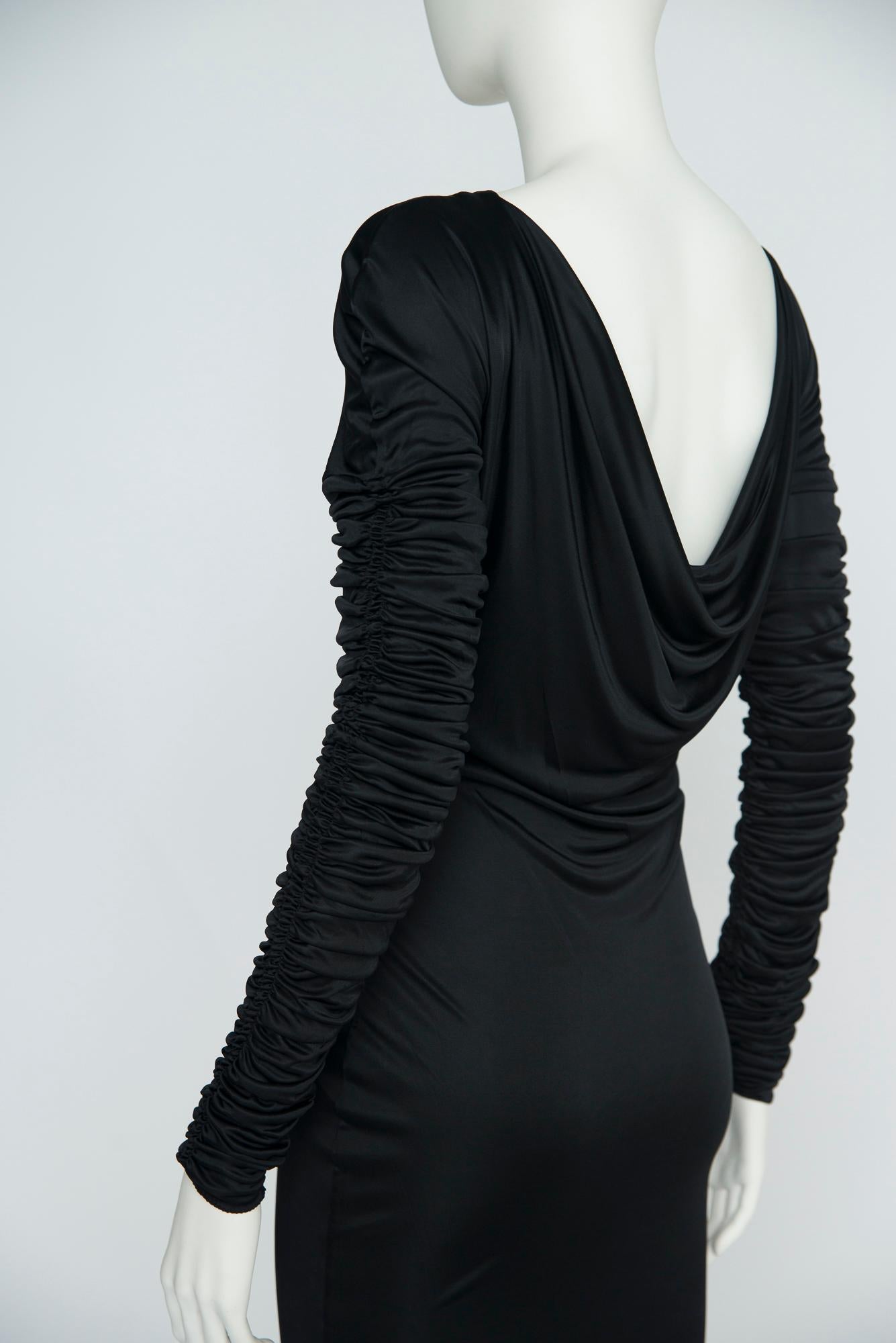 Dieses Gucci-Cocktailkleid für Frühjahr/Sommer 2003 ist aus schwarzem, glattem Stretch-Satin-Jersey gefertigt und passt sich Ihrer Körperform an. Während die Rückseite einen glamourösen, drapierten Kuttenausschnitt offenbart, verleihen die