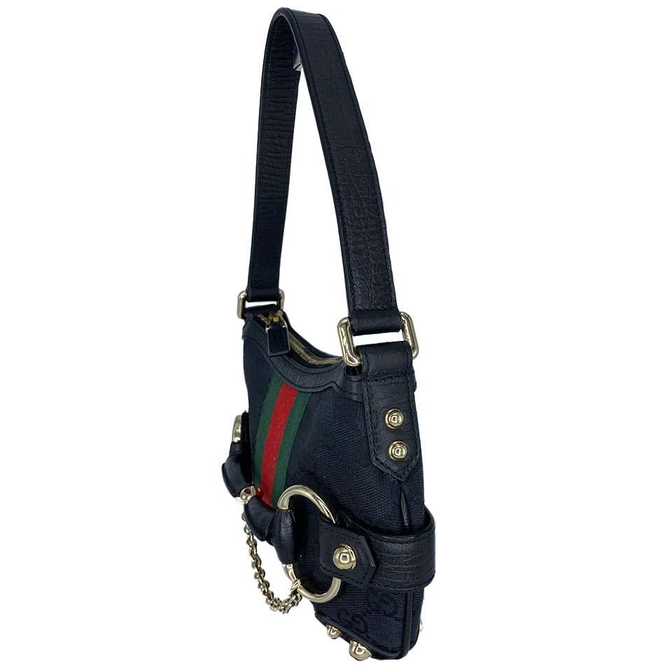 Presenting a mini GG horse-bit hobo bag by Tom Ford for Gucci. This early 2000's bag features the classic 'GG' monogram weave accented with the red and green Gucci web down the center of both the front and back. An oversized horse-bit adorns the