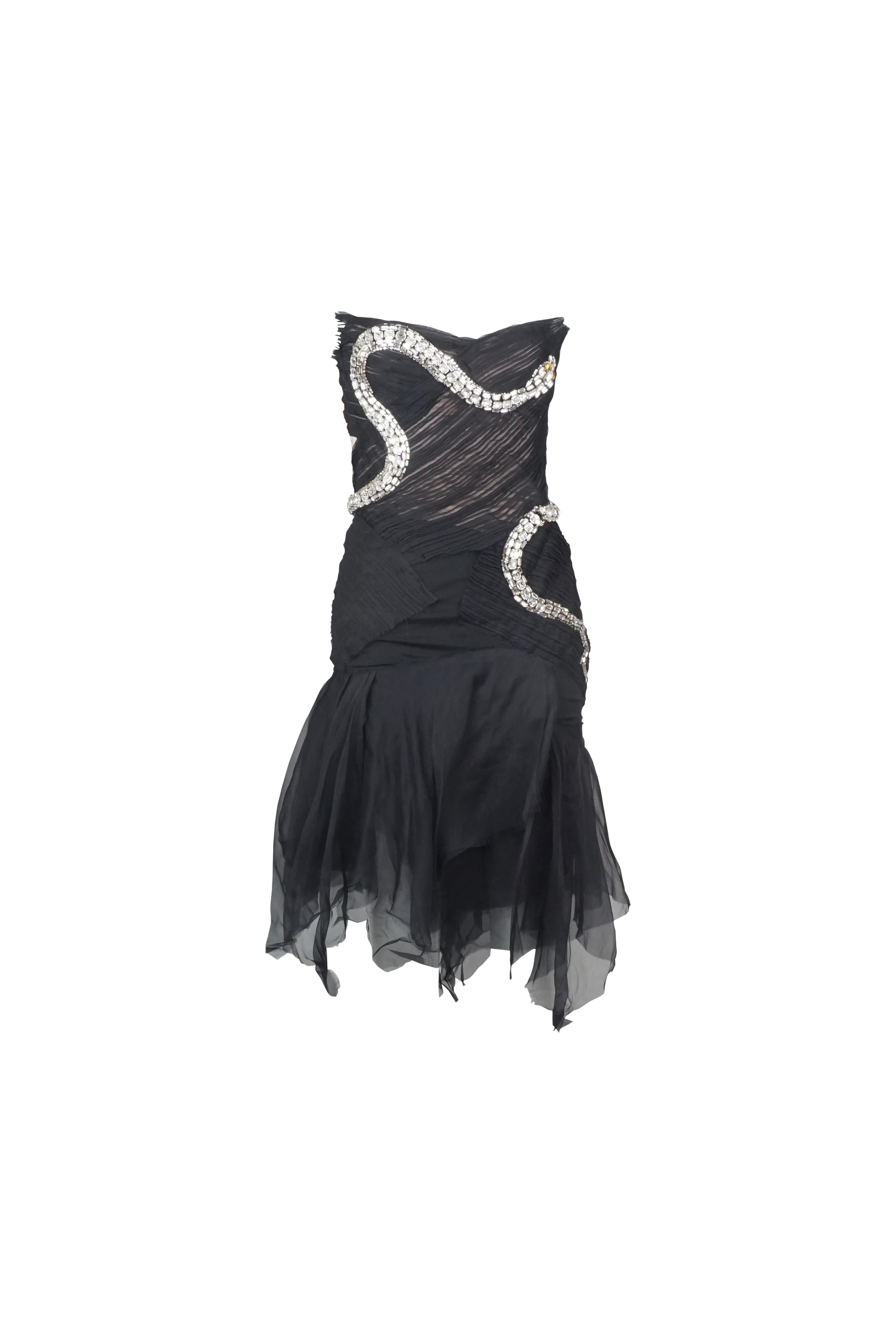 This is a dramatic and glamorous strapless cocktail dress that exudes bold elegance. The dress features a fitted bodice with an asymmetrical design, crafted from black ruched fabric that creates a textured and sophisticated look. Embellished with