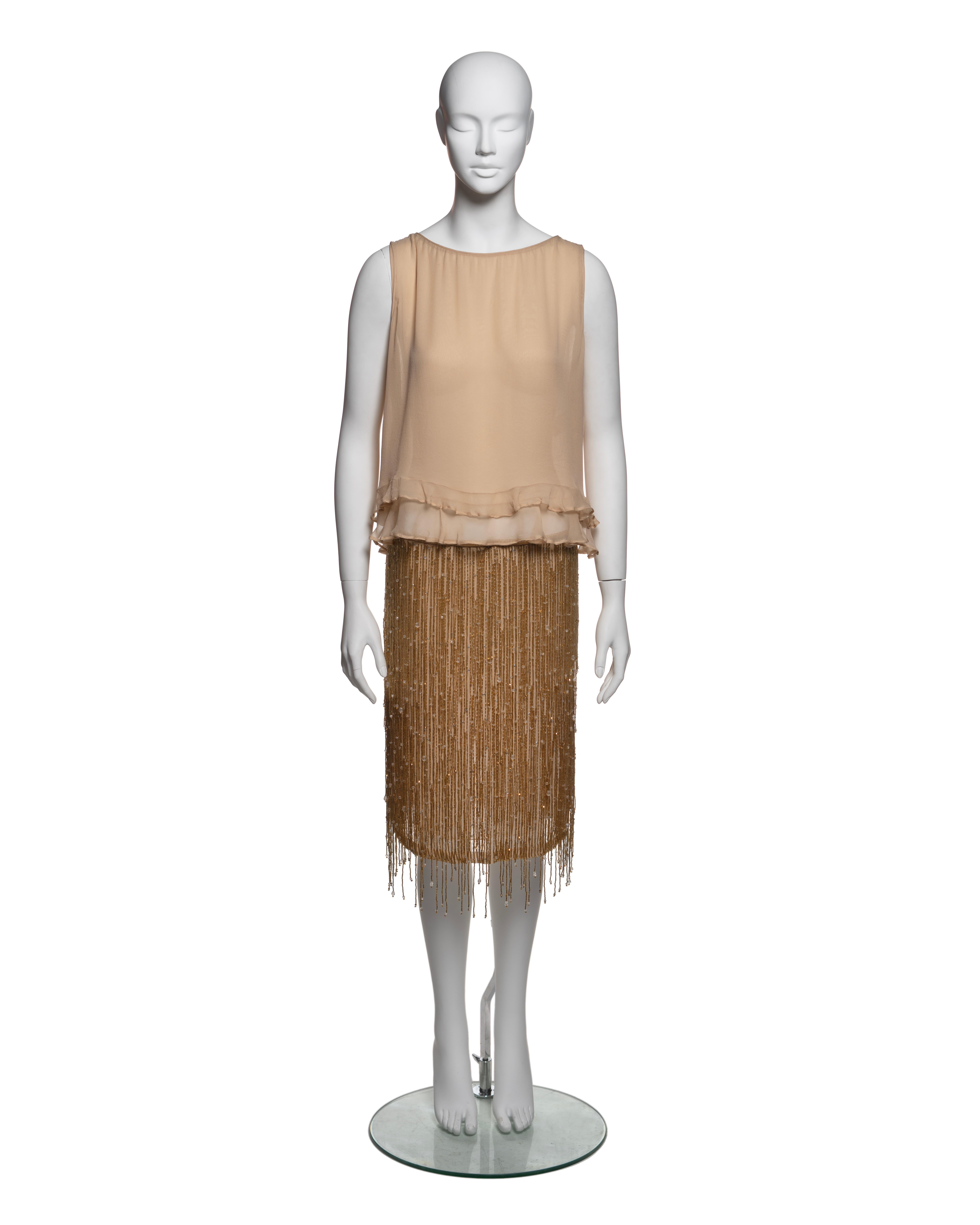 This Gucci by Tom Ford runway ensemble features a beige silk top with layered ruffles at the hem, paired with a beaded silk skirt. The skirt is embellished with long strands of gold bugle beads, mixed with faceted beads and small round beads,