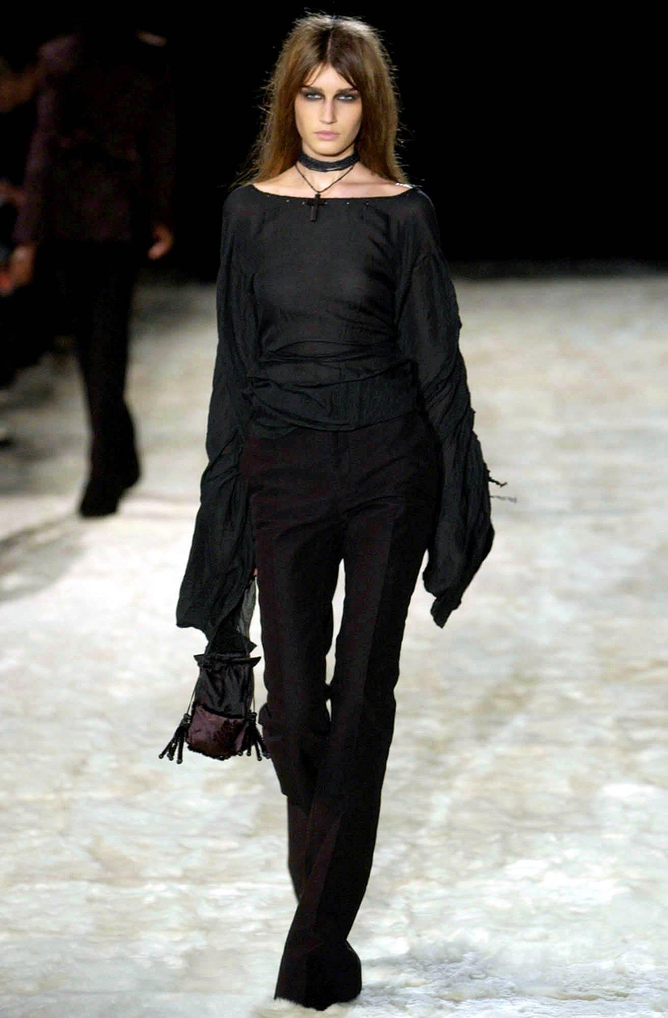 - Diseñado por Tom Ford 
- Vendido por Skof.Archive
- Colección Otoño-Invierno 2002
- Top Bondage Negro Semitransparente
- Mangas globo con fruncidos y fruncidos elaborados en toda la longitud
- Elementos de cordón ajustables en las mangas
- Corsé