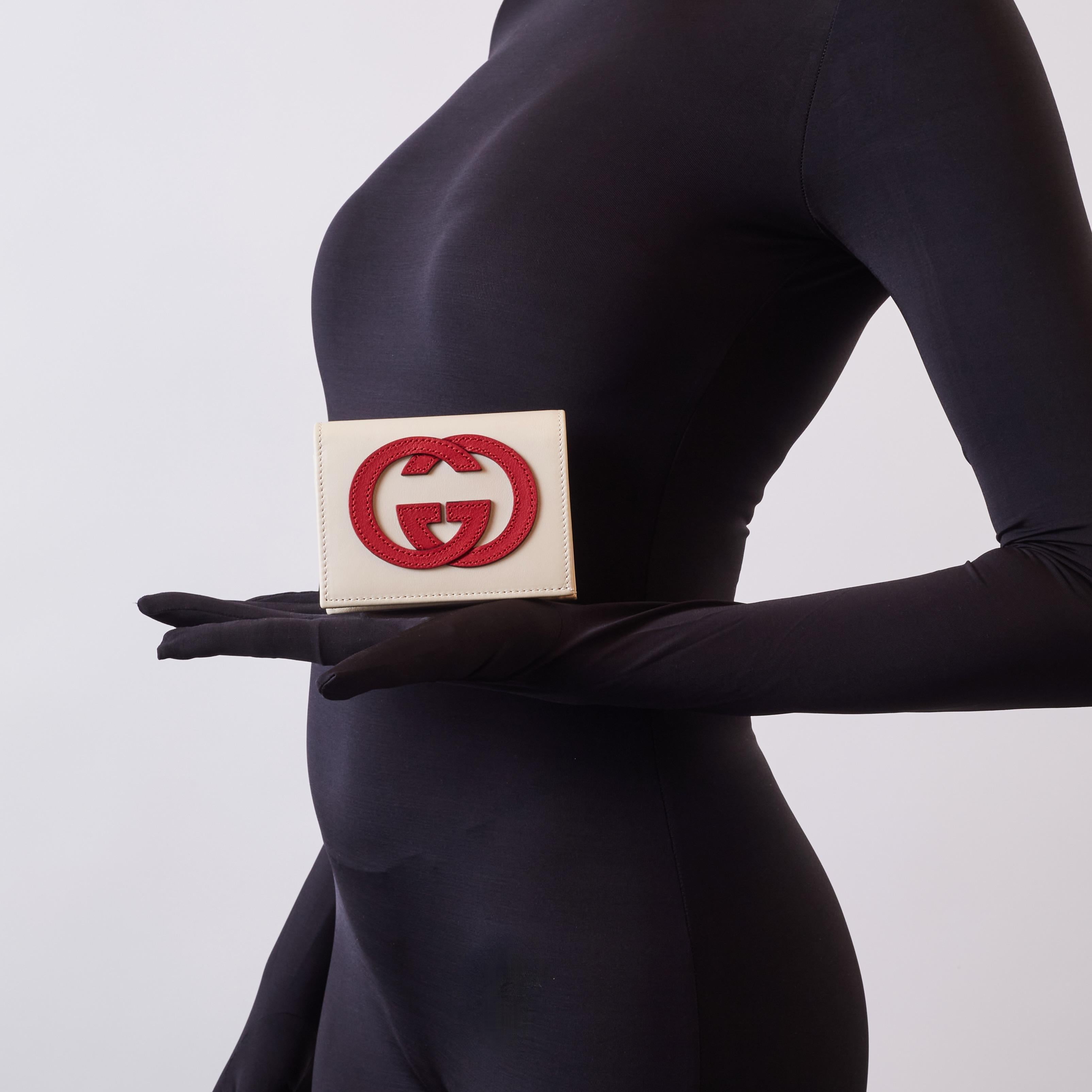 Dieses Kartenetui ist aus strukturiertem Kalbsleder in Off-White gefertigt und zeigt ein rotes, ineinandergreifendes G-Logo auf der Vorderseite. Die Klappe öffnet sich zu einem Innenraum aus passendem Leder mit Kartenfächern, einem Scheinfach und
