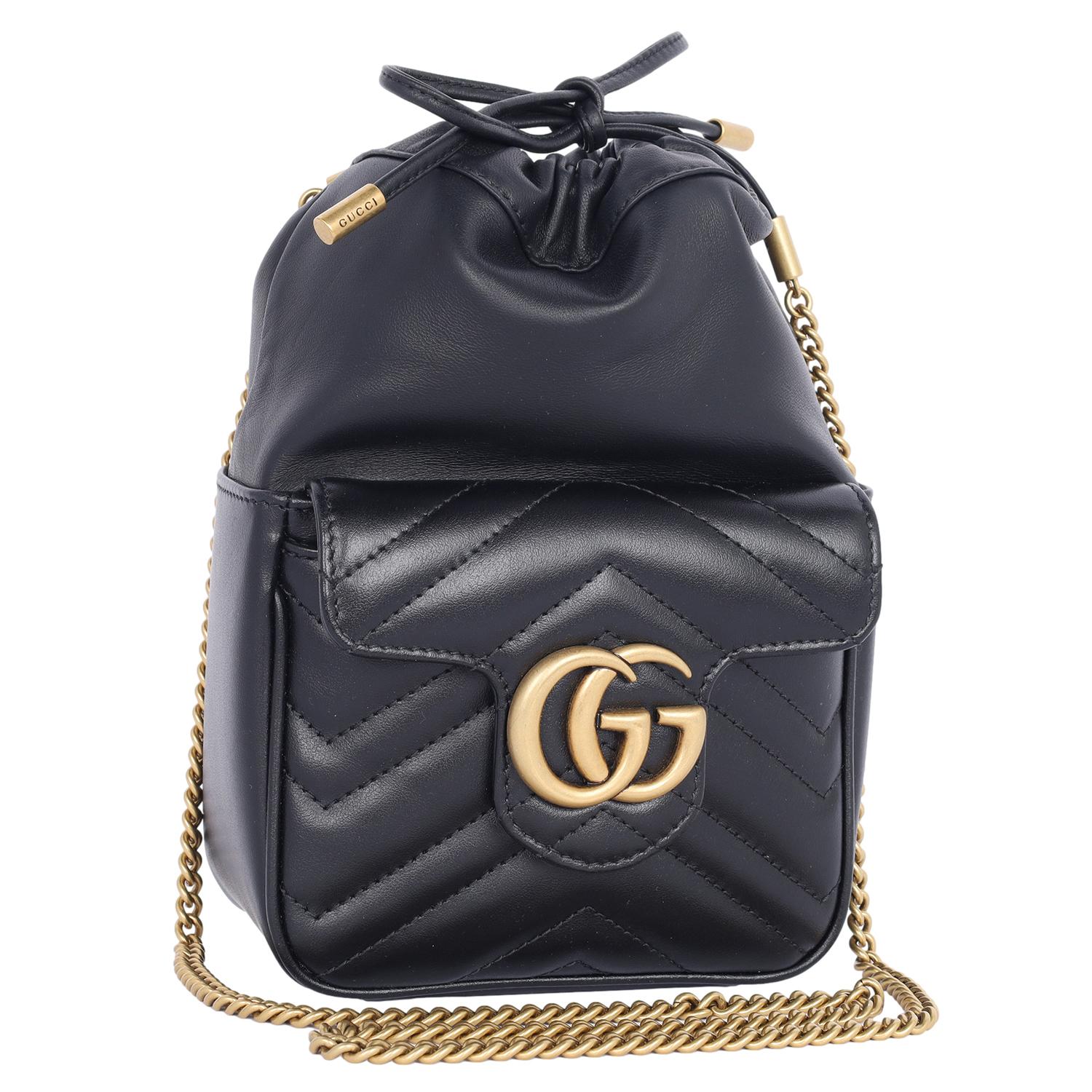 Authentic NEW Gucci Calfskin Matelasse Mini GG Marmont 2.0 Bucket Bag in Black. This bucket bag features soft calfskin leather with a black chevron quilted front pocket, aged gold chain strap, top leather cinch drawstring closure, aged gold GG logo