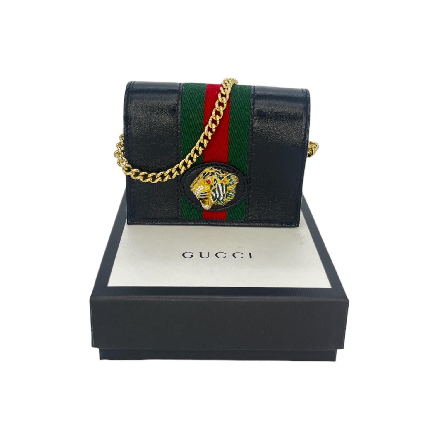 Gucci Web Rajah Chain Card Case Wallet. This chic wallet is crafted of calfskin leather in black and features an optional gold chain strap, a green and red webbed stripe, and a crystal-encrusted tiger head. The flap opens to a leather interior with