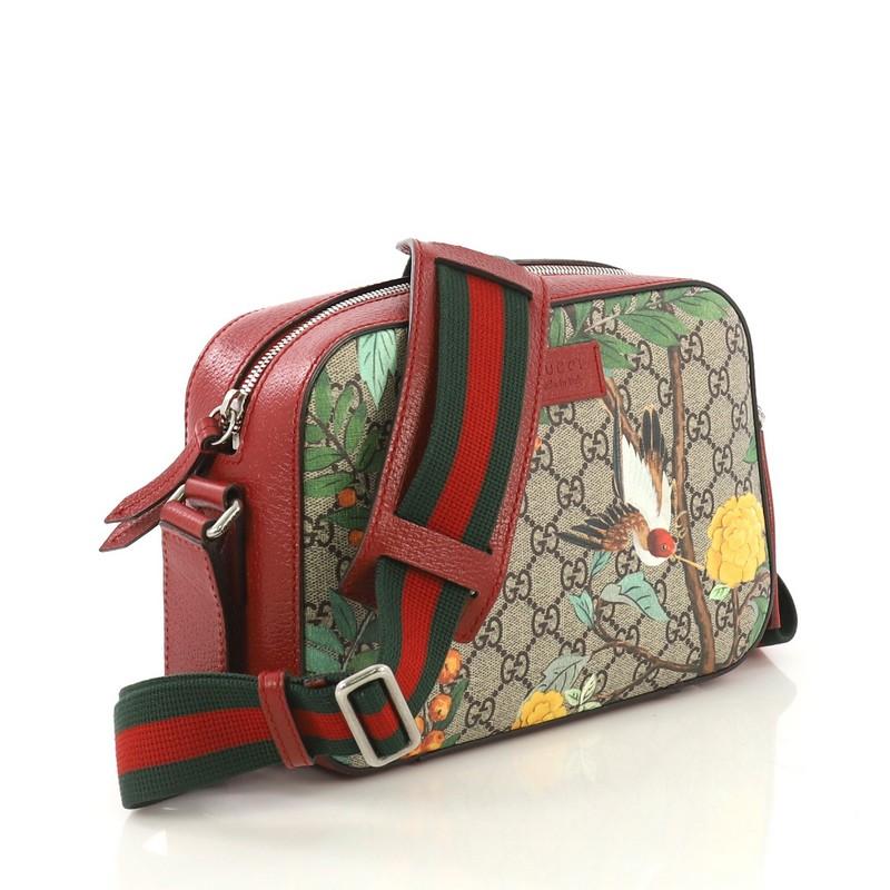 This Gucci Camera Shoulder Bag Tian Print GG Coated Canvas Medium, crafted from multicolor Tian Print coated canvas, features red and green web strap, leather trims and gold-tone hardware accents. Its zip closure opens to a brown suede interior with