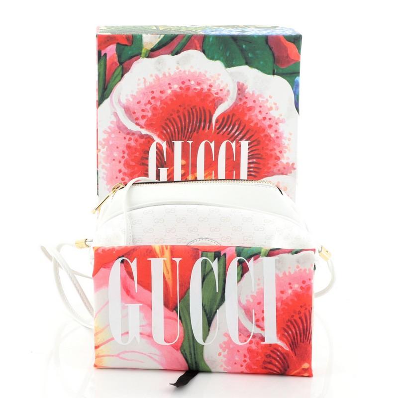 This Gucci Candy Crossbody Bag Mini GG Coated Canvas, crafted in white GG supreme coated canvas, features thin shoulder strap, interlocking GG stud at center and gold-tone hardware. Its zip closure opens to a blue printed fabric interior.