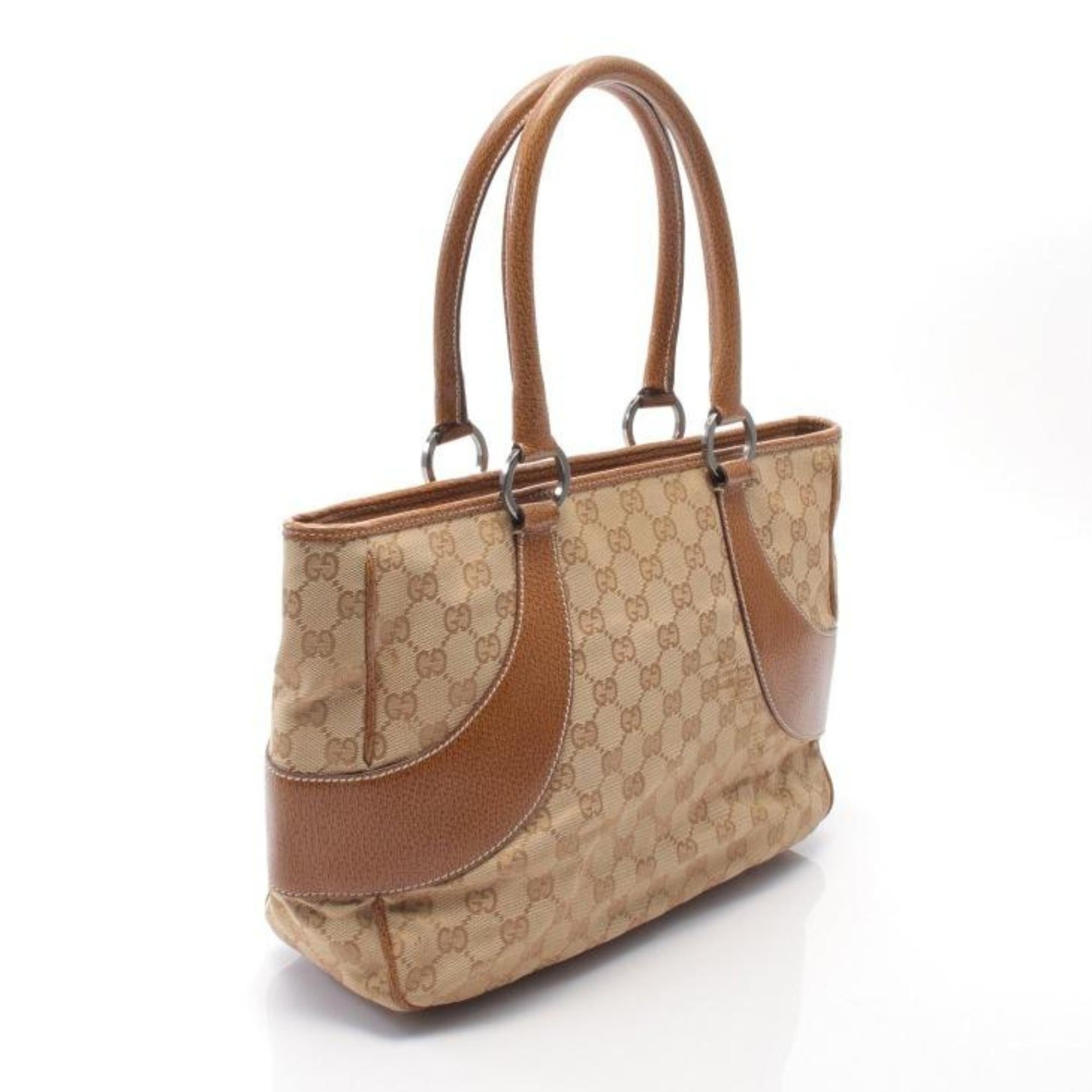This tote is finely constructed of Gucci GG monogram canvas in beige. The bag features beige leather trim, dual rolled leather top handles, dark silver hardware and top zip closure. The top opens to a brown fabric interior with a zipper