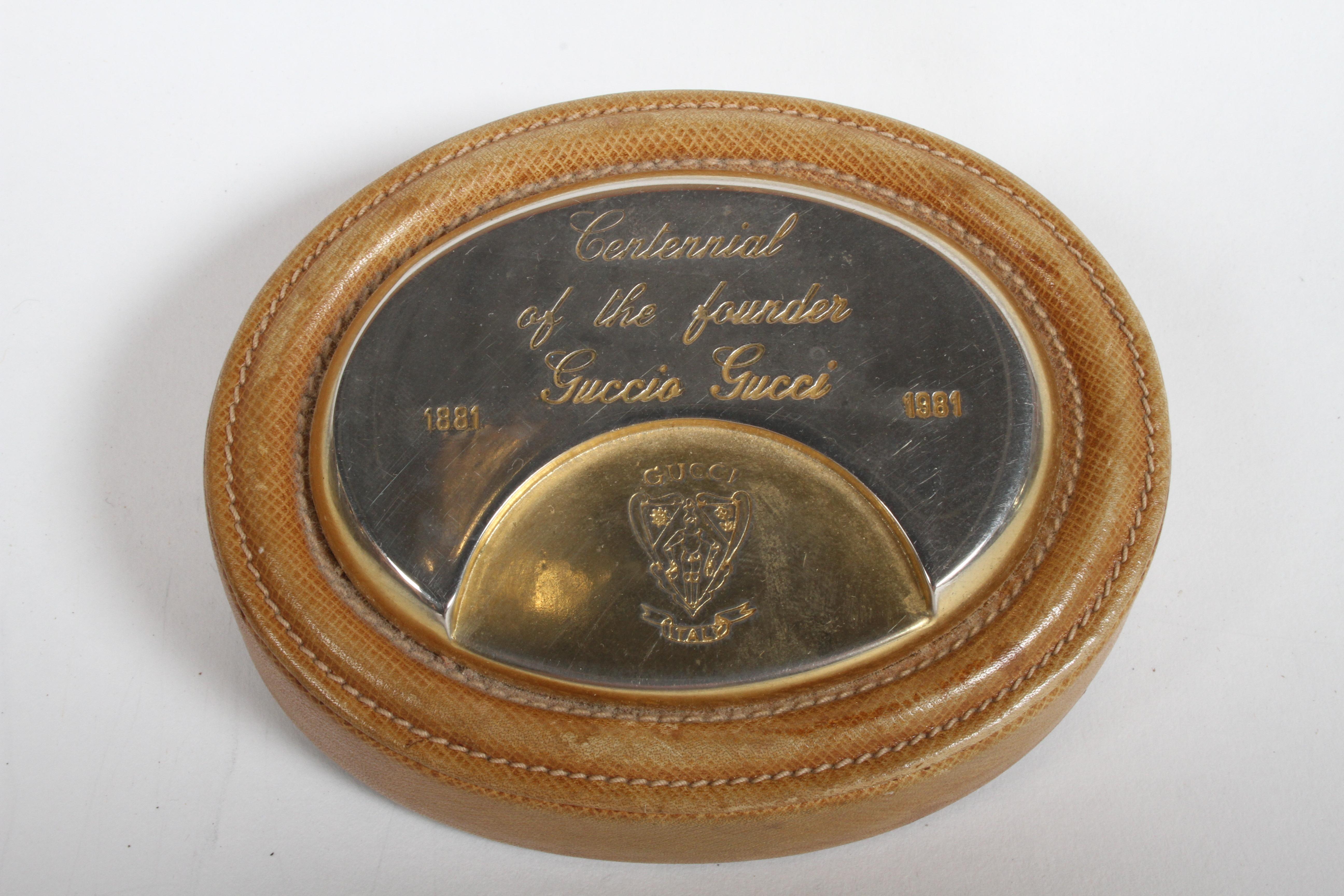 From the estate of the former owners of the Gucci Store in Plaza Frontenac - St. Louis. Is a Gucci desk paperweight, leather and plated gold, for the centennial of the founder Guccio Gucci (1891-1991). Leather and plating show wear.