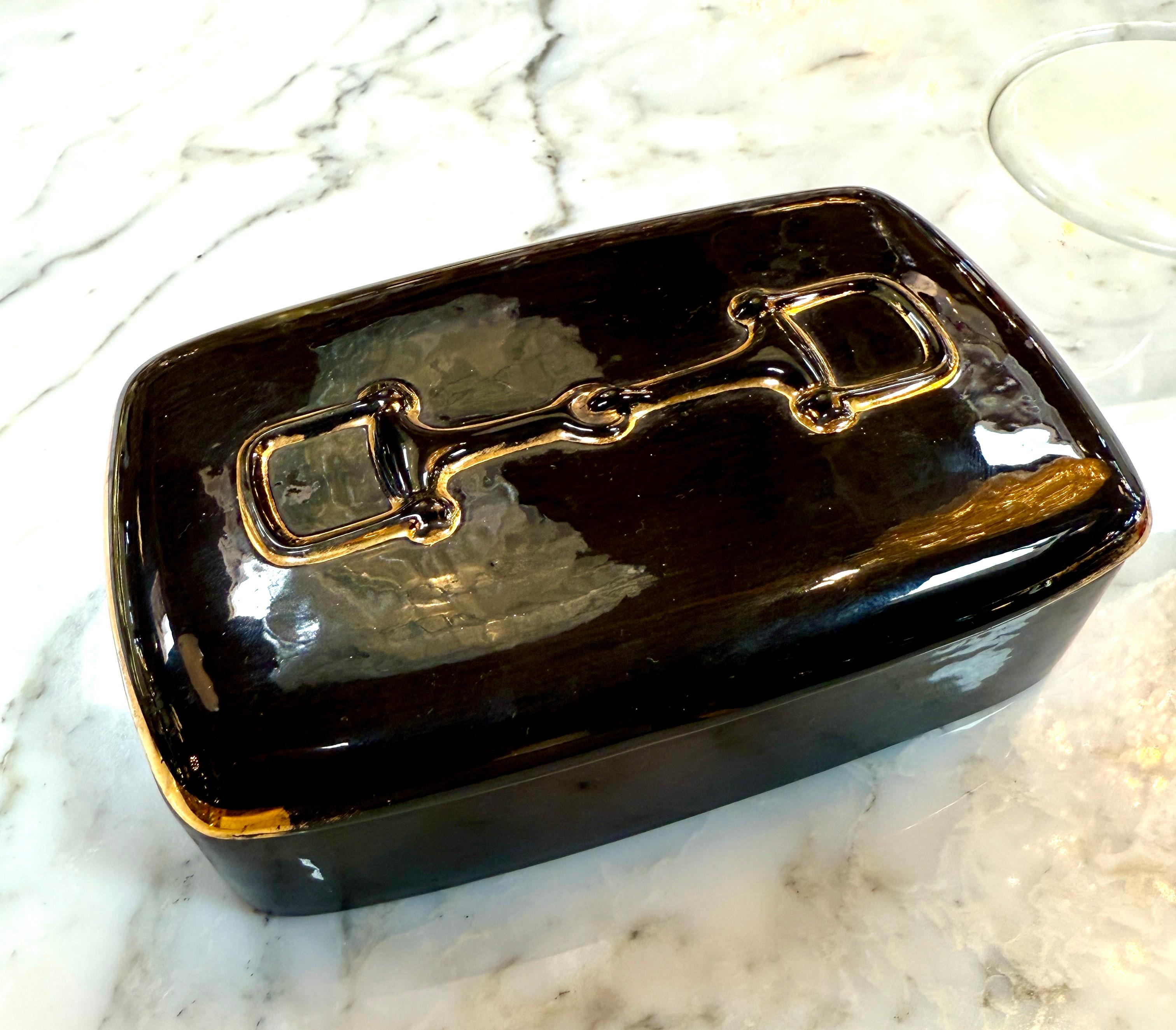 Elegante y refinado, este neceser de cerámica de Gucci data de los años 80 y refleja la icónica mezcla de lujo y funcionalidad de la marca. El esmalte verde intenso se acentúa con la clásica insignia dorada de Gucci en la tapa, ofreciendo un