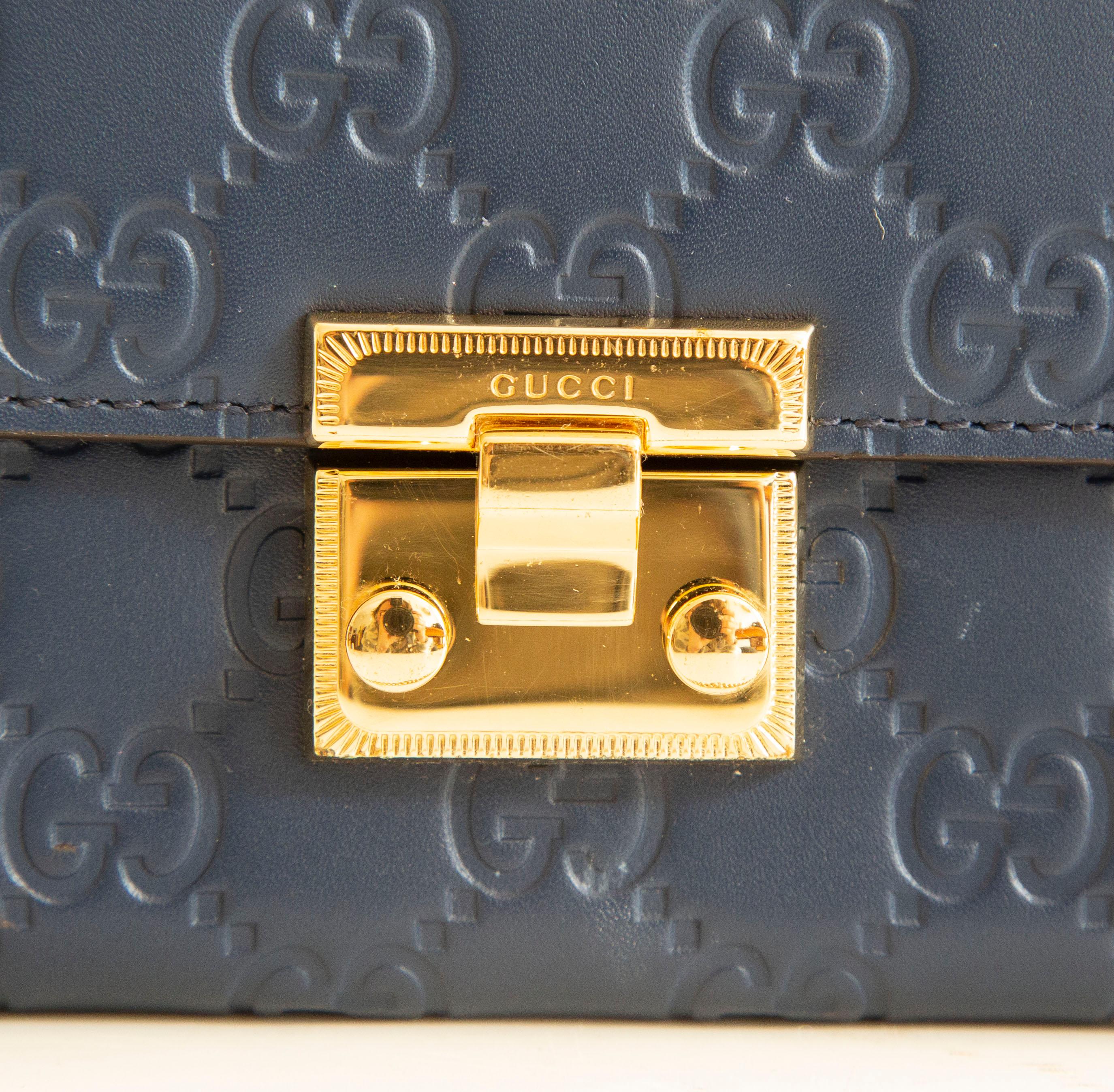 An authentic Gucci chain bi-fold wallet shoulder bag/clutch. The bag features a blue Guccissima embossed leather exterior and gold-toned hardware. The interior is lined with blue leather and is separated into two main compartments by a zipped pouch.