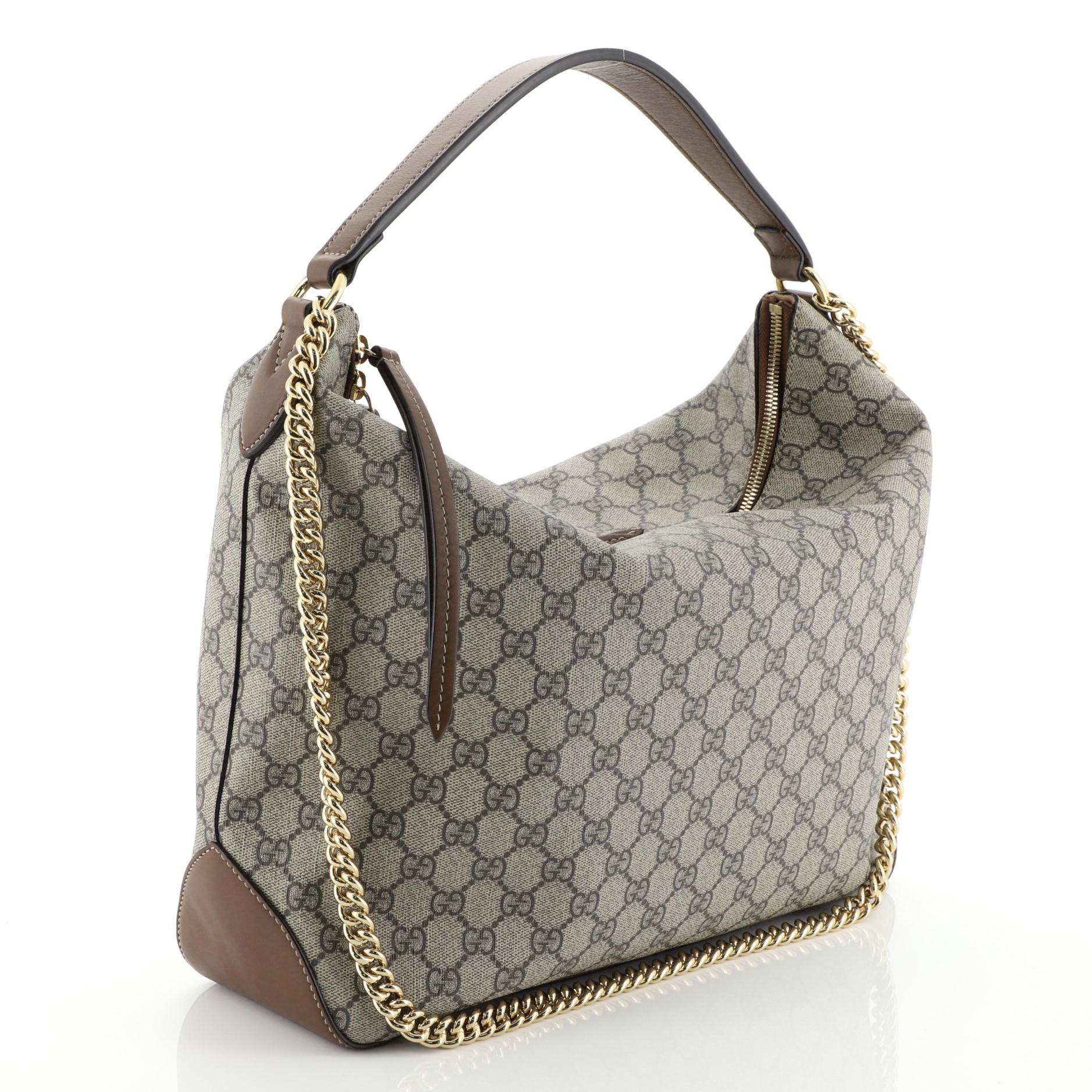 This Gucci Chain Hobo GG Coated Canvas Large, crafted in brown GG coated canvas, features looped leather handle, chain link shoulder strap and gold-tone hardware. Its zip closure opens to a brown microfiber interior with side zip and slip pockets.