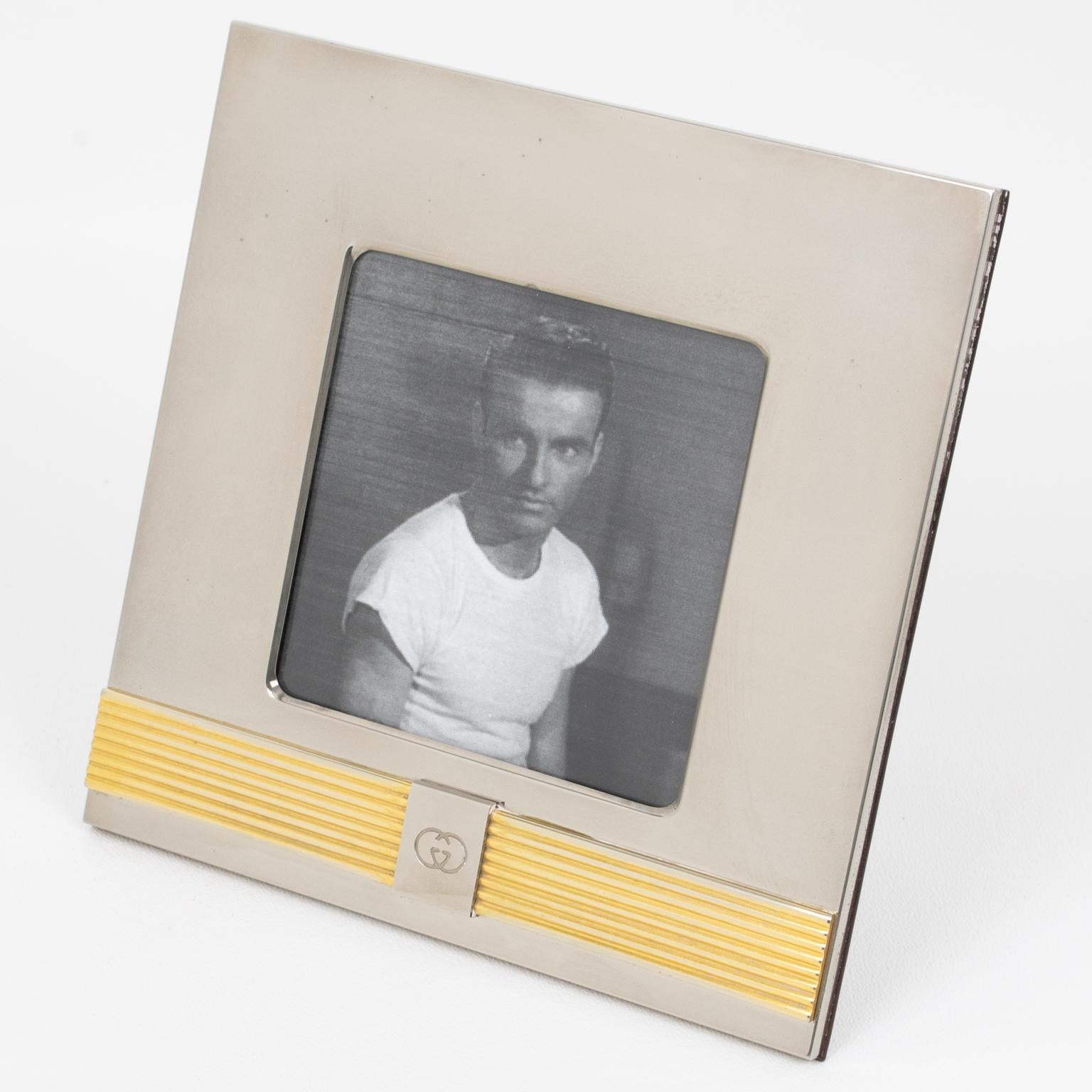 Italian designer Gucci designed this luxury picture photo frame. The piece was crafted in Italy circa 1980. The deco piece boasts a square shape made of chromed metal with a gold plate belt-shaped carved striped accent on the lower edge. The GG logo