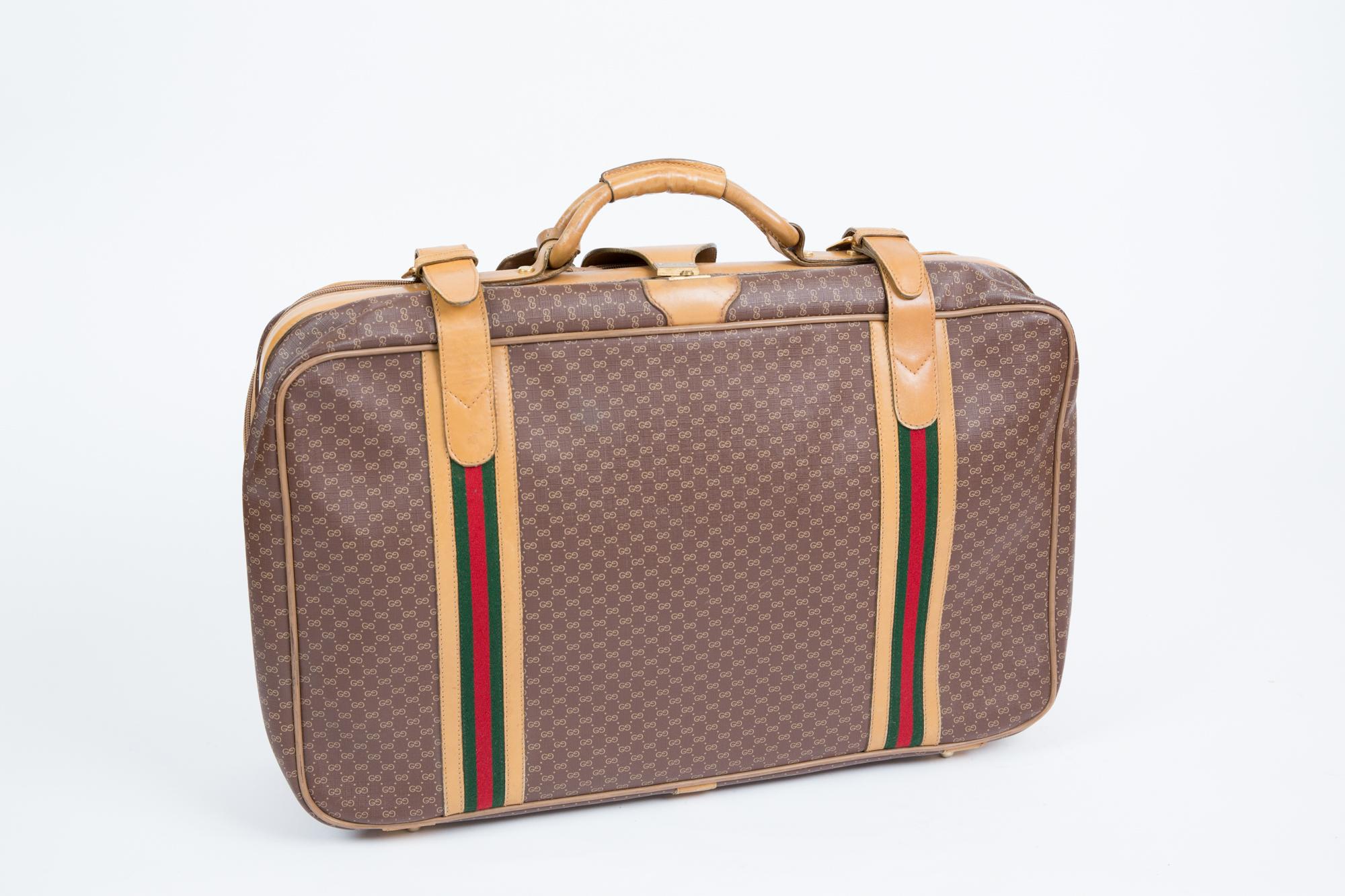Gucci coffee- brown GG Supreme coated canvas travel suitcase featuring  top rounded camel leather handle, suitcase trimmed with the House the green and red Web stripe, round top handle, camel leather trims, two chunky brass zippers and a camel