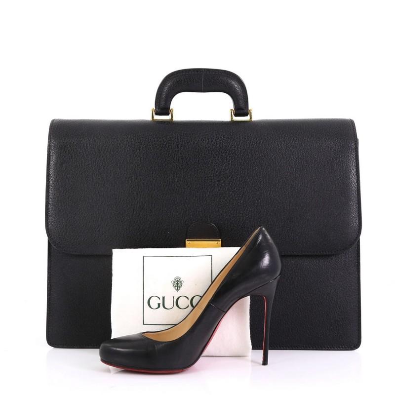 This Gucci Combination Lock Briefcase Leather Large, crafted in black leather, features single leather top handle, frontal flap, and gold-tone hardware. Its combination lock closure opens to a beige microfiber interior with side zip and slip