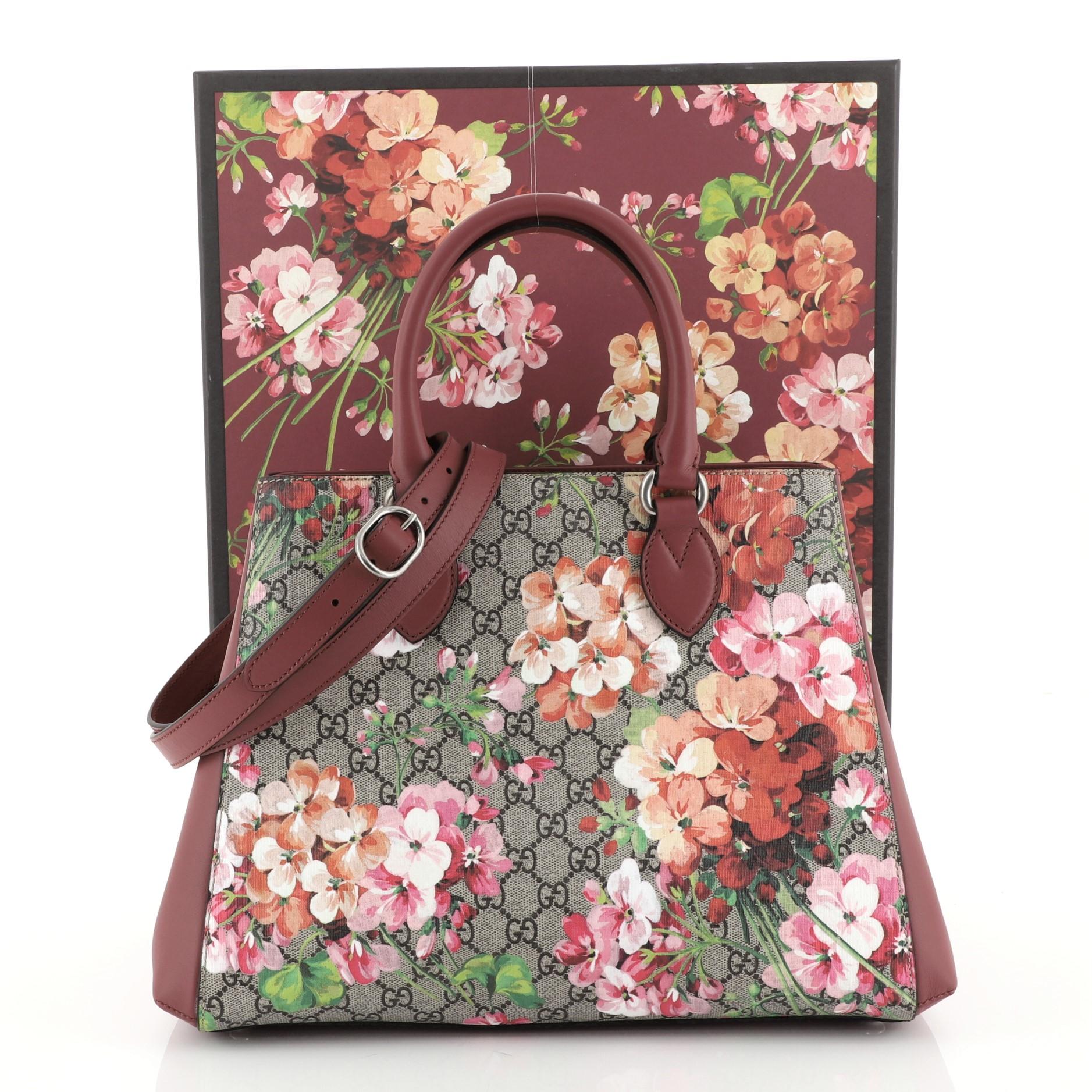 This Gucci Convertible Shopping Tote Blooms Print GG Coated Canvas Large, crafted from purple blooms print GG coated canvas, features dual rolled leather handles, leather side panels, and silver-tone hardware. It opens to a brown microfiber interior