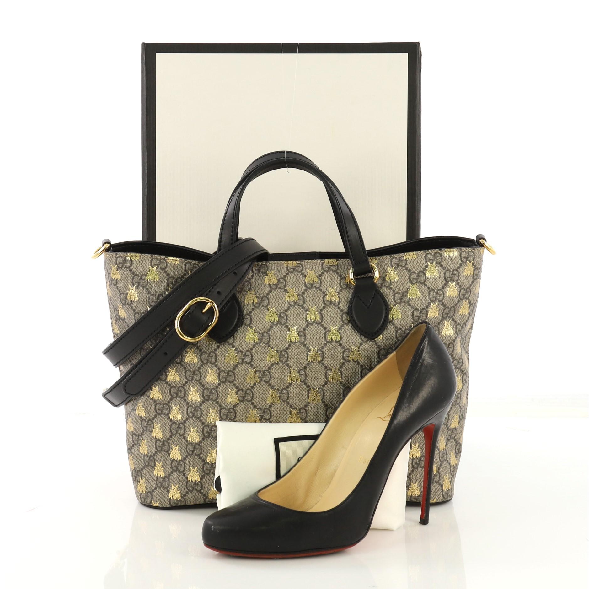 This Gucci Convertible Soft Tote Printed GG Coated Canvas Small, crafted from brown printed GG coated canvas and black leather, features dual flat handles, golden bee printed throughout and gold-tone hardware. Its hidden magnetic snap closure opens