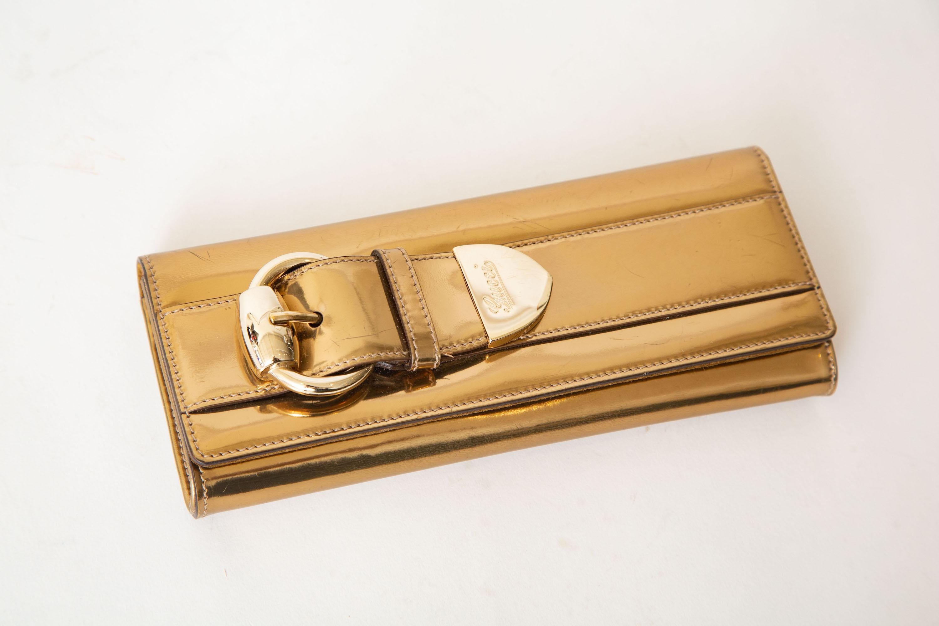 This ever so chic and slim Italian Gucci gold copper buckle small clutch fits an I phone 11 and Up. It is from 2000. It was designed by Frida Giannini for Gucci. We have just had it taken to a high end shoe repair to shine up and partially remove a