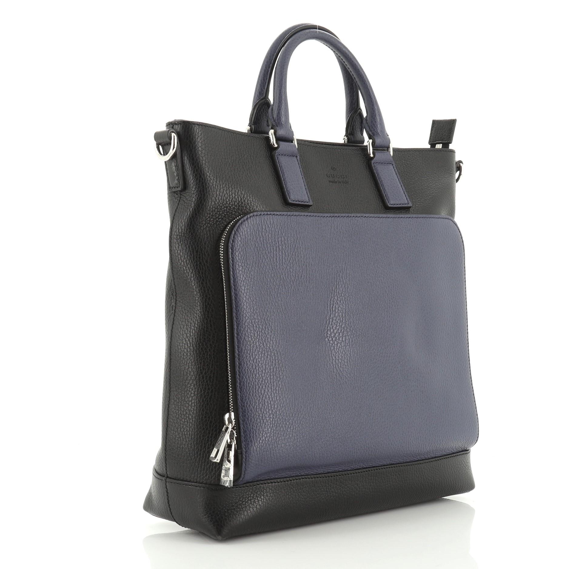 This Gucci Cosmopolis Tote Leather, crafted in bicolor black and blue leather, features dual-rolled leather handles, embossed Gucci logo at front, front zip pocket and silver-tone hardware. Its zip closure opens to a black fabric interior with zip